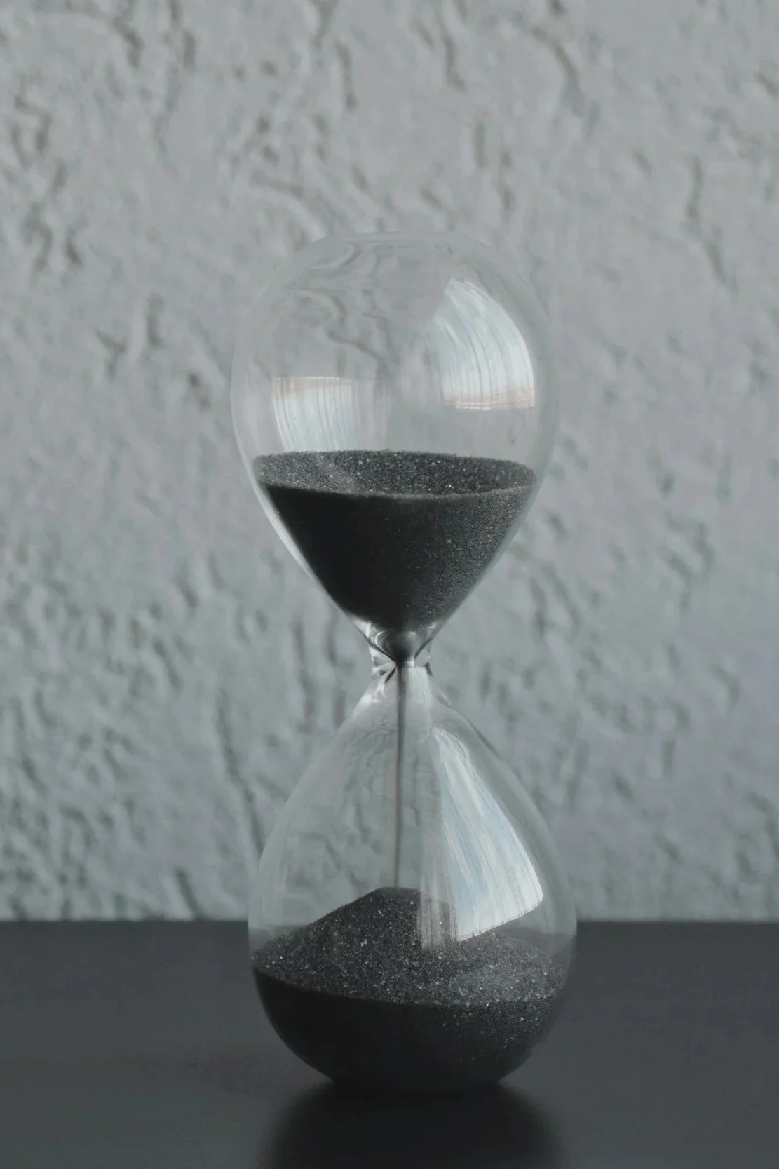grayscale hourglass concrete wall background dark table surface