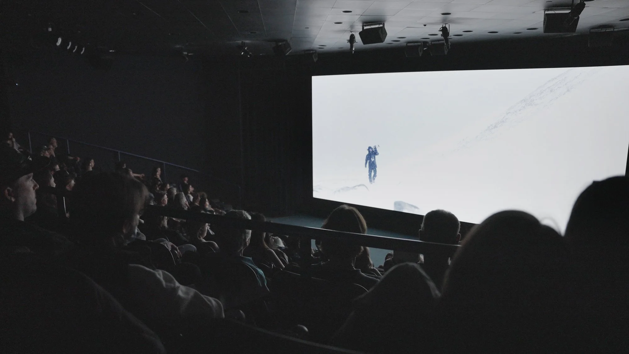 People watching a movie about a snowy mountain expedition in a dark theater