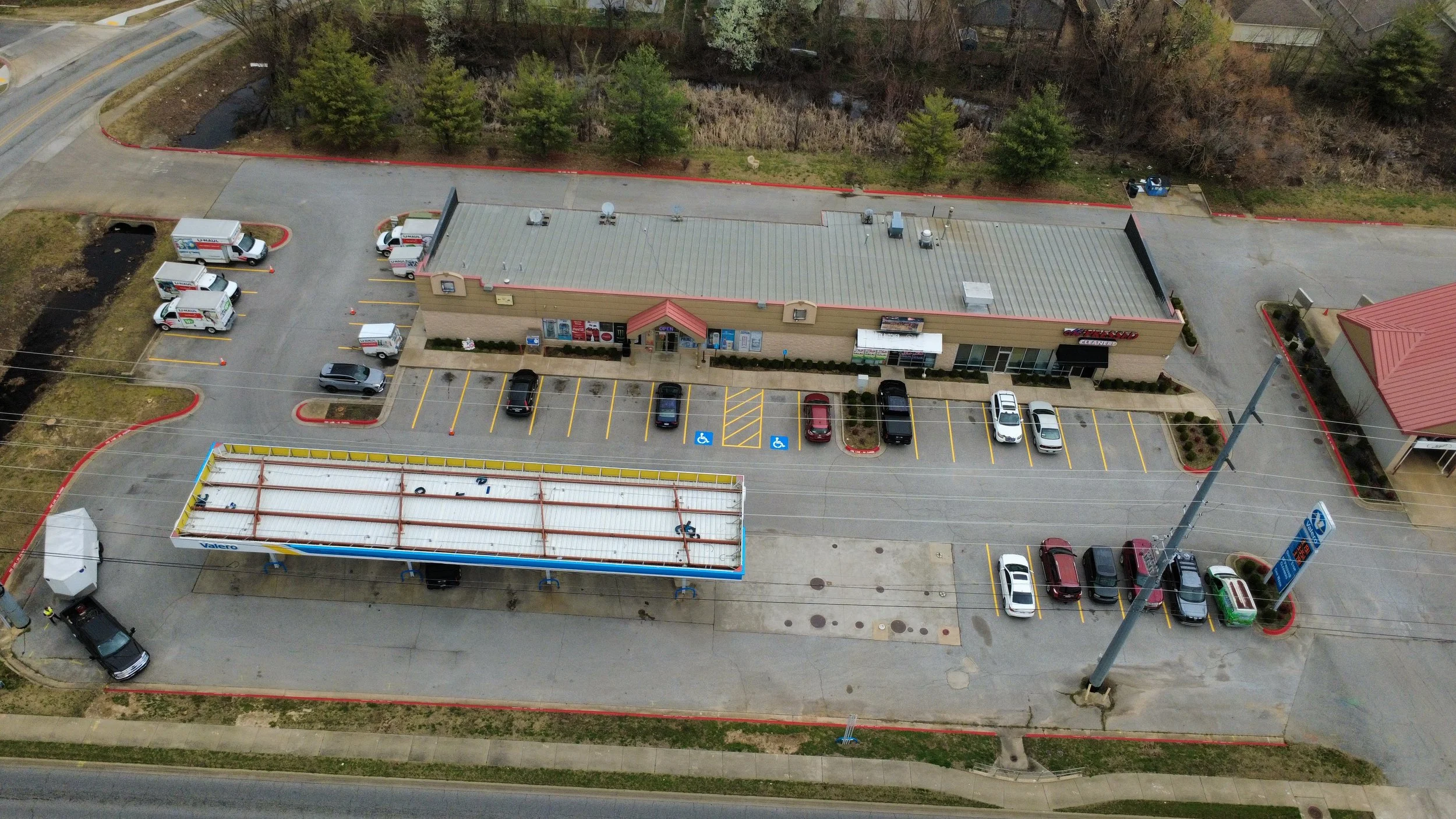 Empty parking lot with painted lines, surrounded by trees under a cloudy sky.