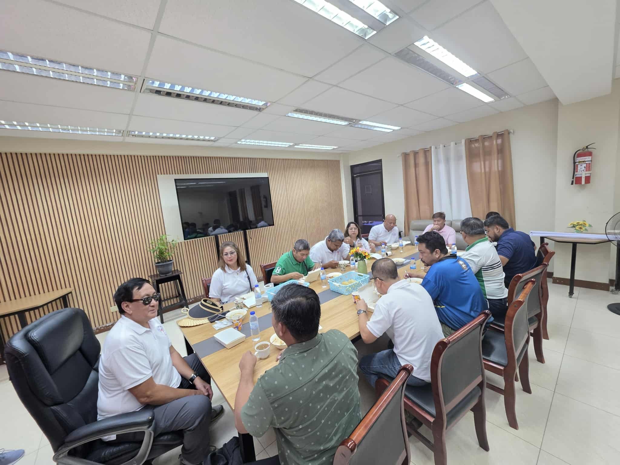 Group of people sitting around a conference table having a meeting or discussion in an office room.