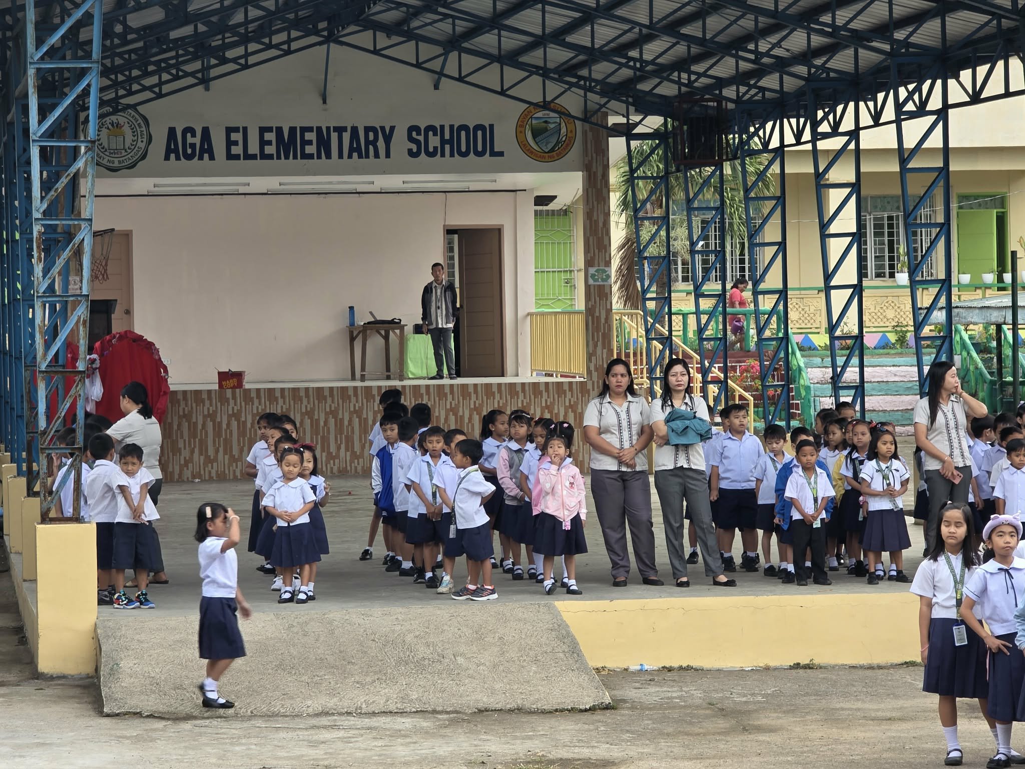 Students in uniform line up in front of AGA Elementary School for a ceremony.