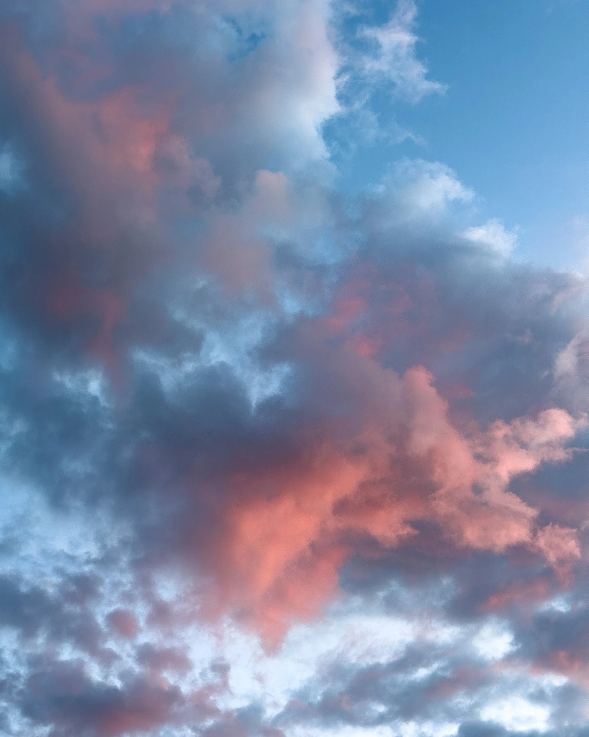 Cloudy sky at sunset with pink and blue hues in the clouds.