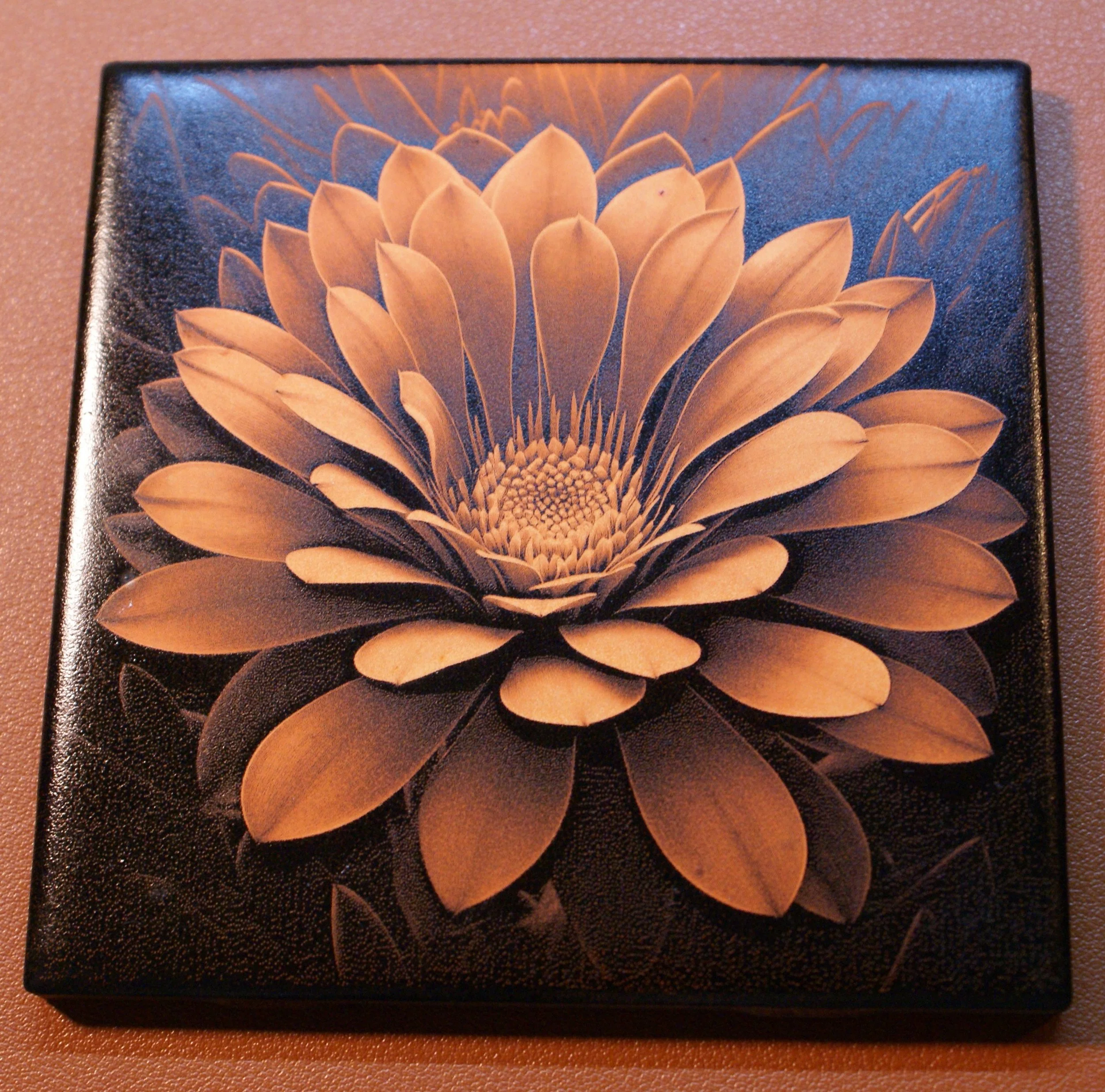 A decorative box with a golden floral design on a black background, resembling a blooming flower with layered petals.