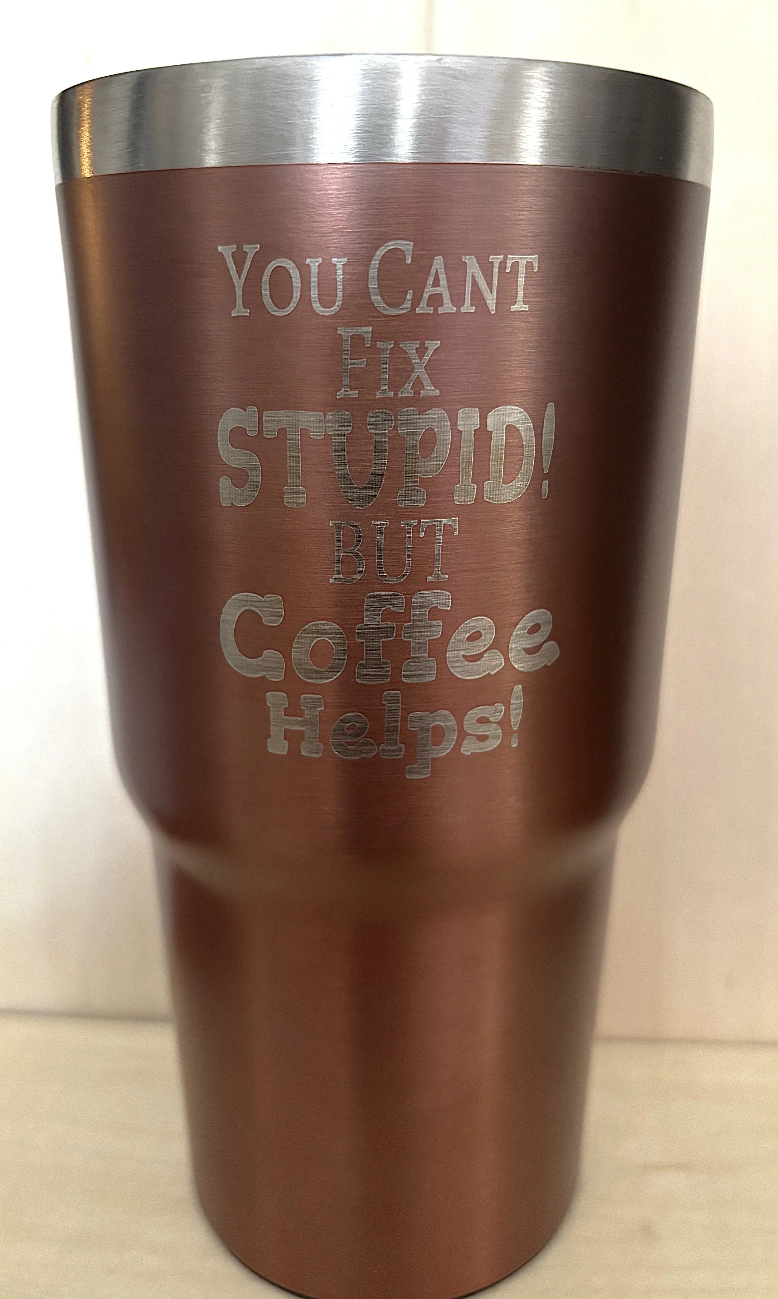 A metallic tumbler with an engraved quote that reads, 'You can't fix stupid! but coffee helps!'