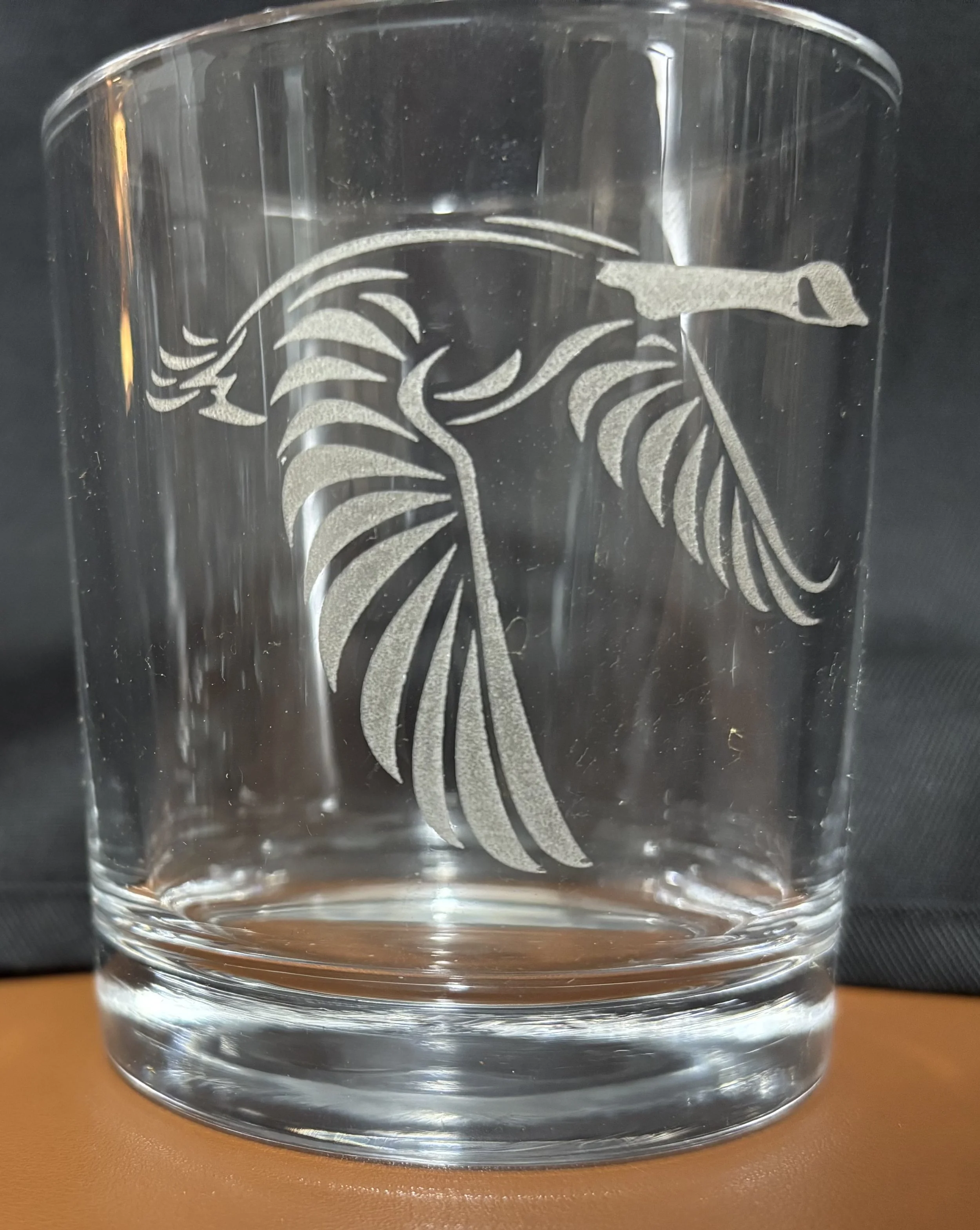 Clear glass tumbler with etched design of a duck and large leaves.