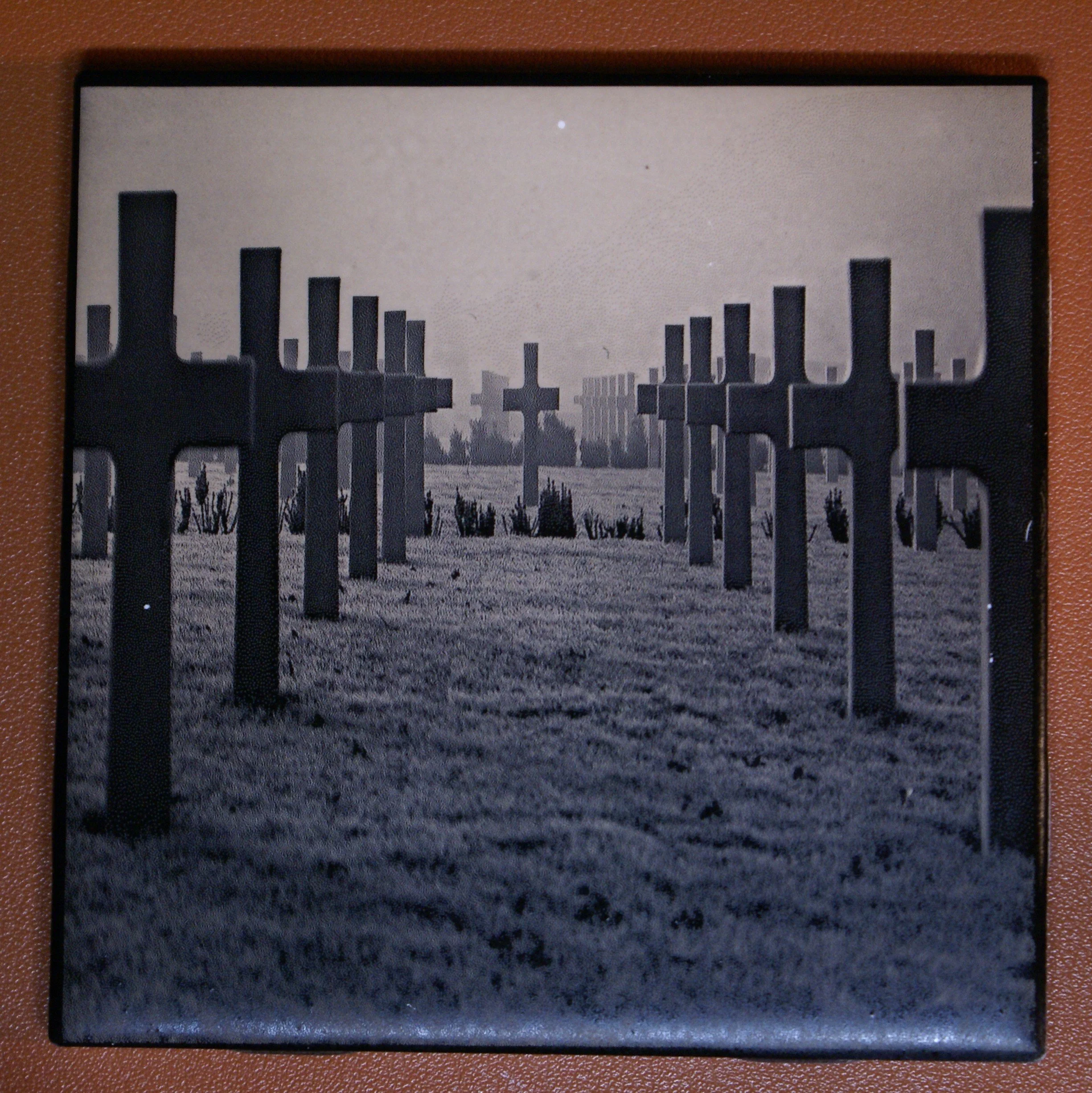 Black and white photo of a cemetery with several crosses and tombstones, with a city skyline in the background.