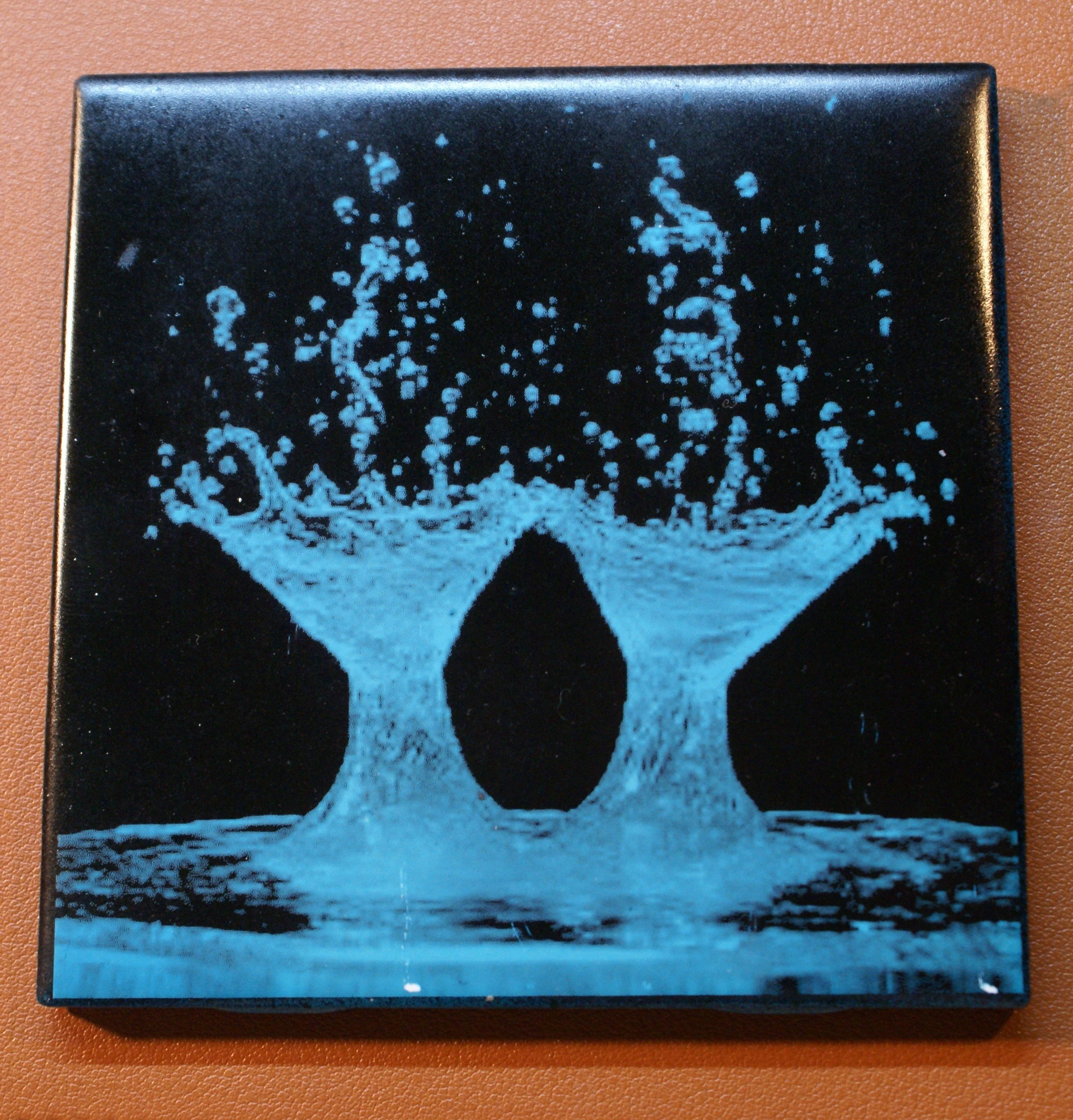 Close-up of black box with blue abstract splash design, resembling water splashing upward.