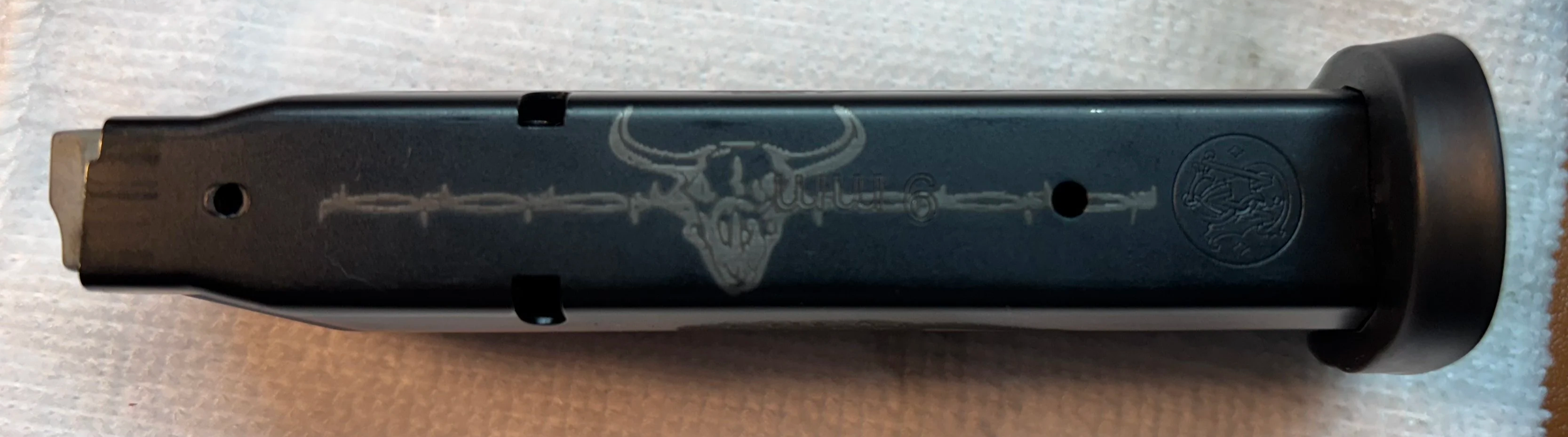Close-up of a firearm magazine with a skull and crossbones design.