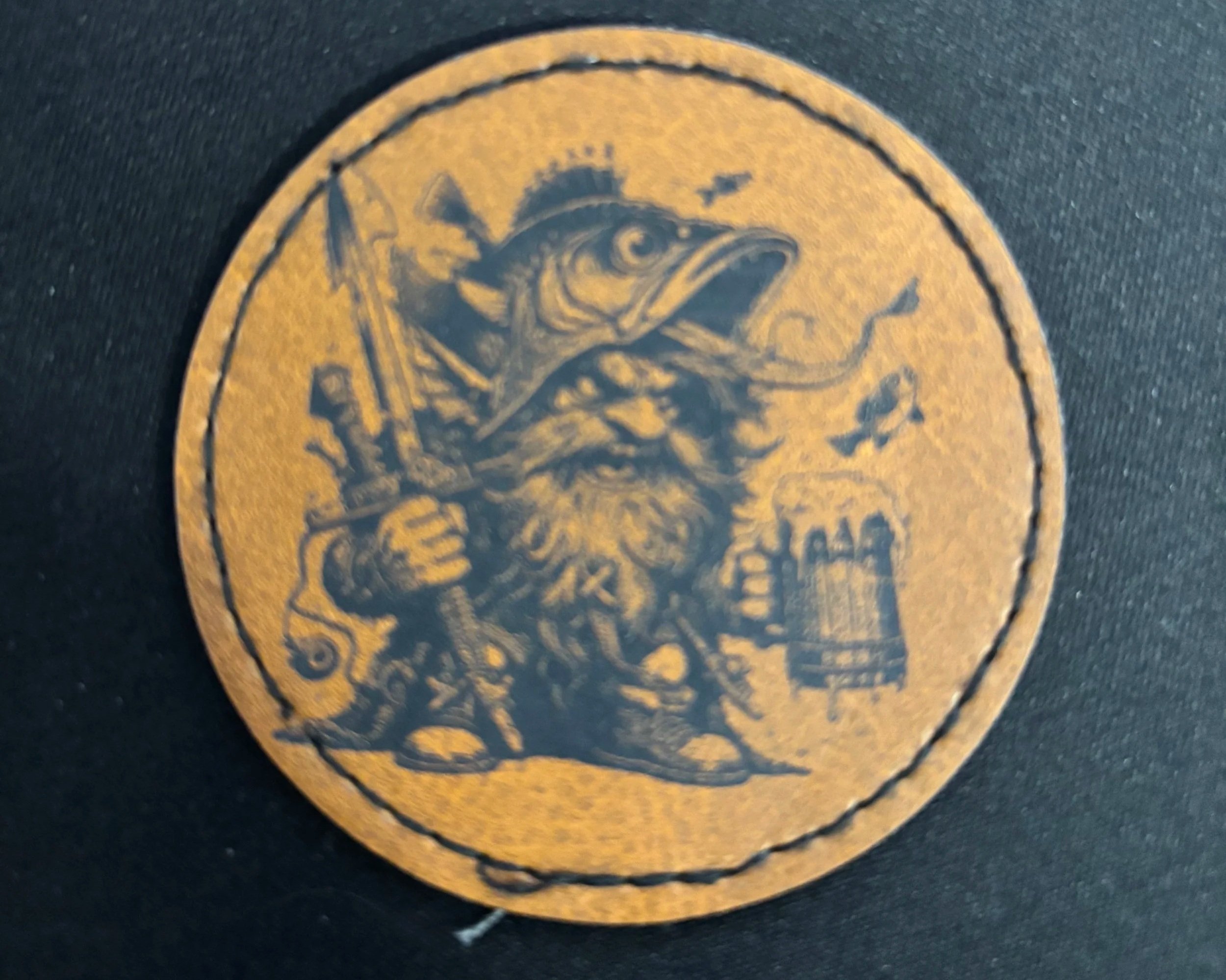 A circular patch with a yellow background, featuring a pirate-like character holding a sword, with a beard, a hat, and a feather, surrounded by various nautical and pirate-themed items.