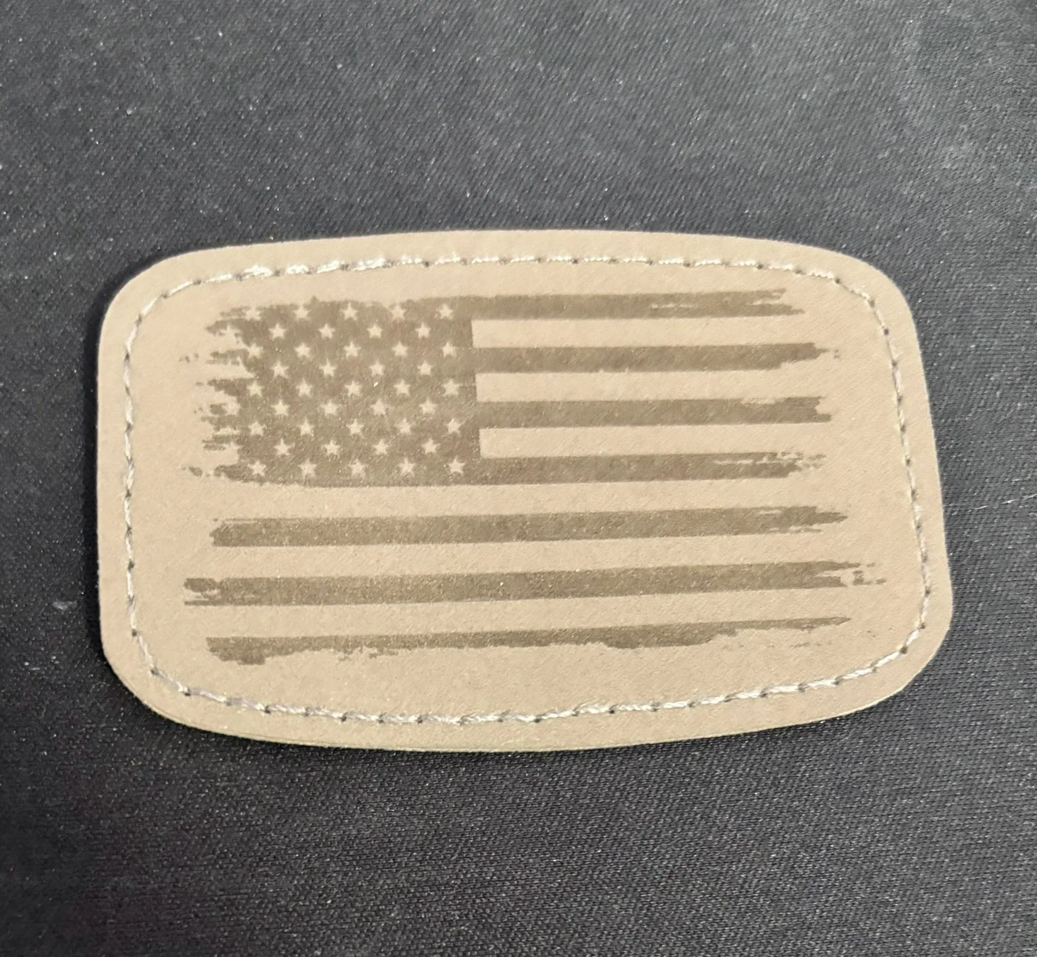 Tan patch with an American flag design and a stitched border.