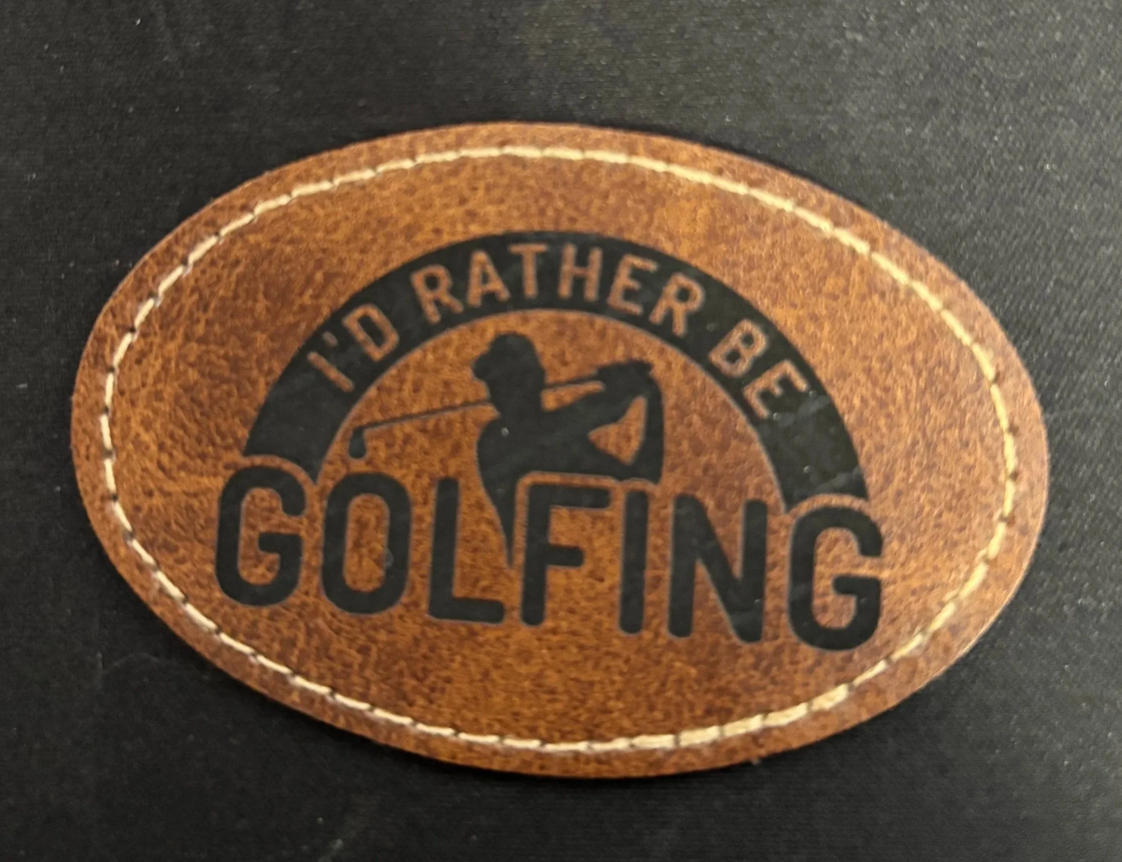 A leather patch with the text 'I'd rather be golfing' and a silhouette of a person swinging a golf club.