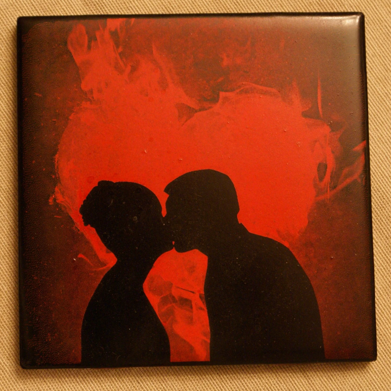 Silhouettes of a man and a woman facing each other and about to kiss, with a red fiery heart in the background.