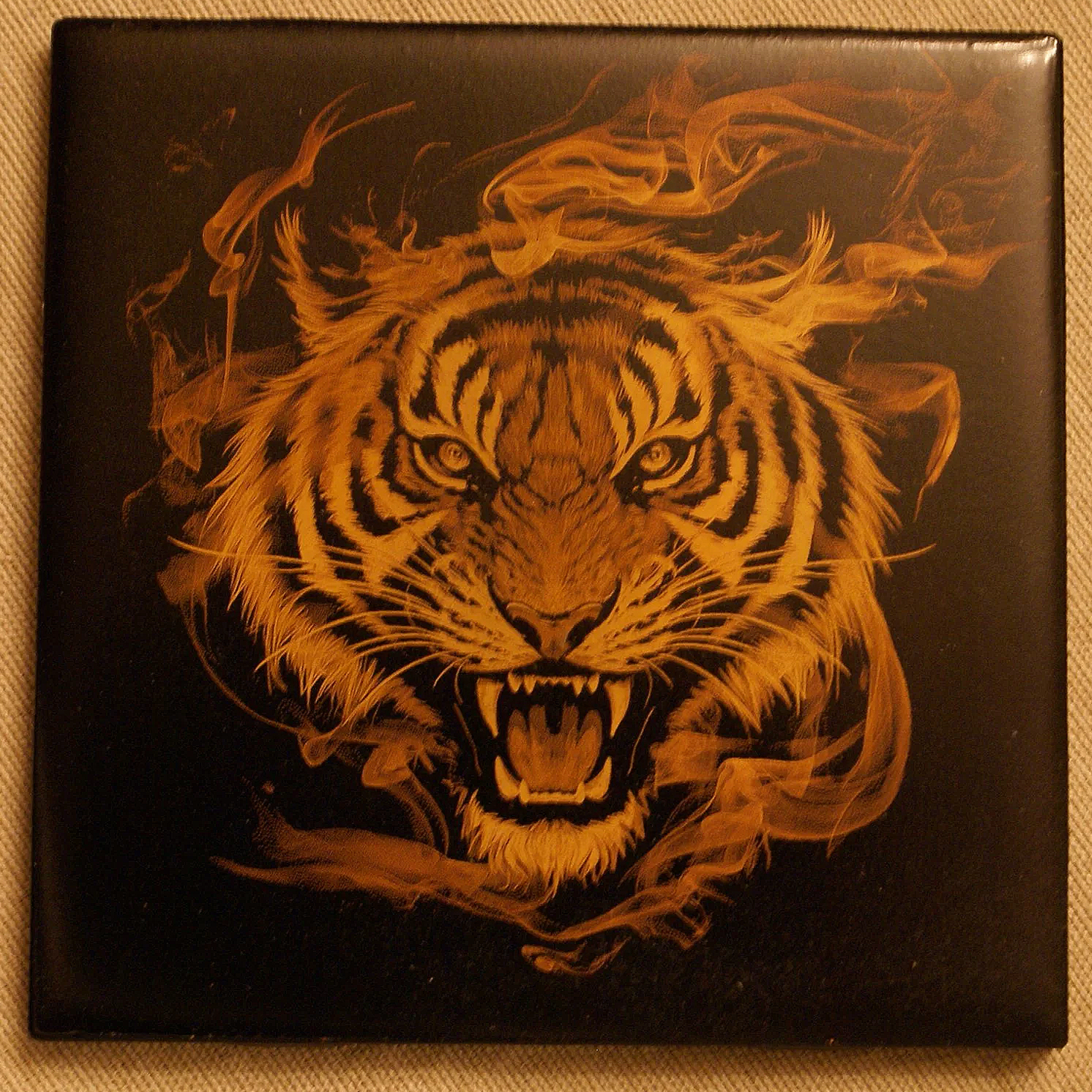 A detailed illustration of a fierce tiger with piercing eyes, roaring mouth, and sharp teeth, surrounded by wisps of smoke or flames, on a dark background.