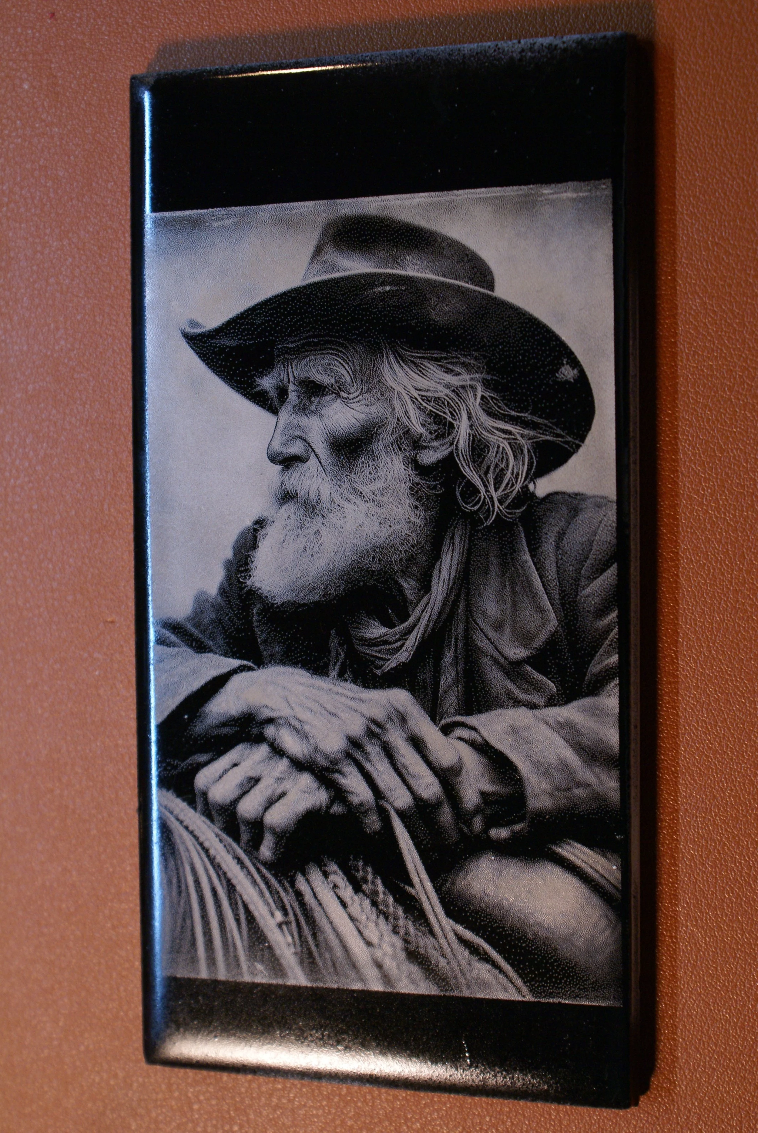 Black and white portrait of an elderly man with a long beard, wearing a wide-brimmed hat and a jacket, with his hands resting in front of him, captured in a realistic art style.