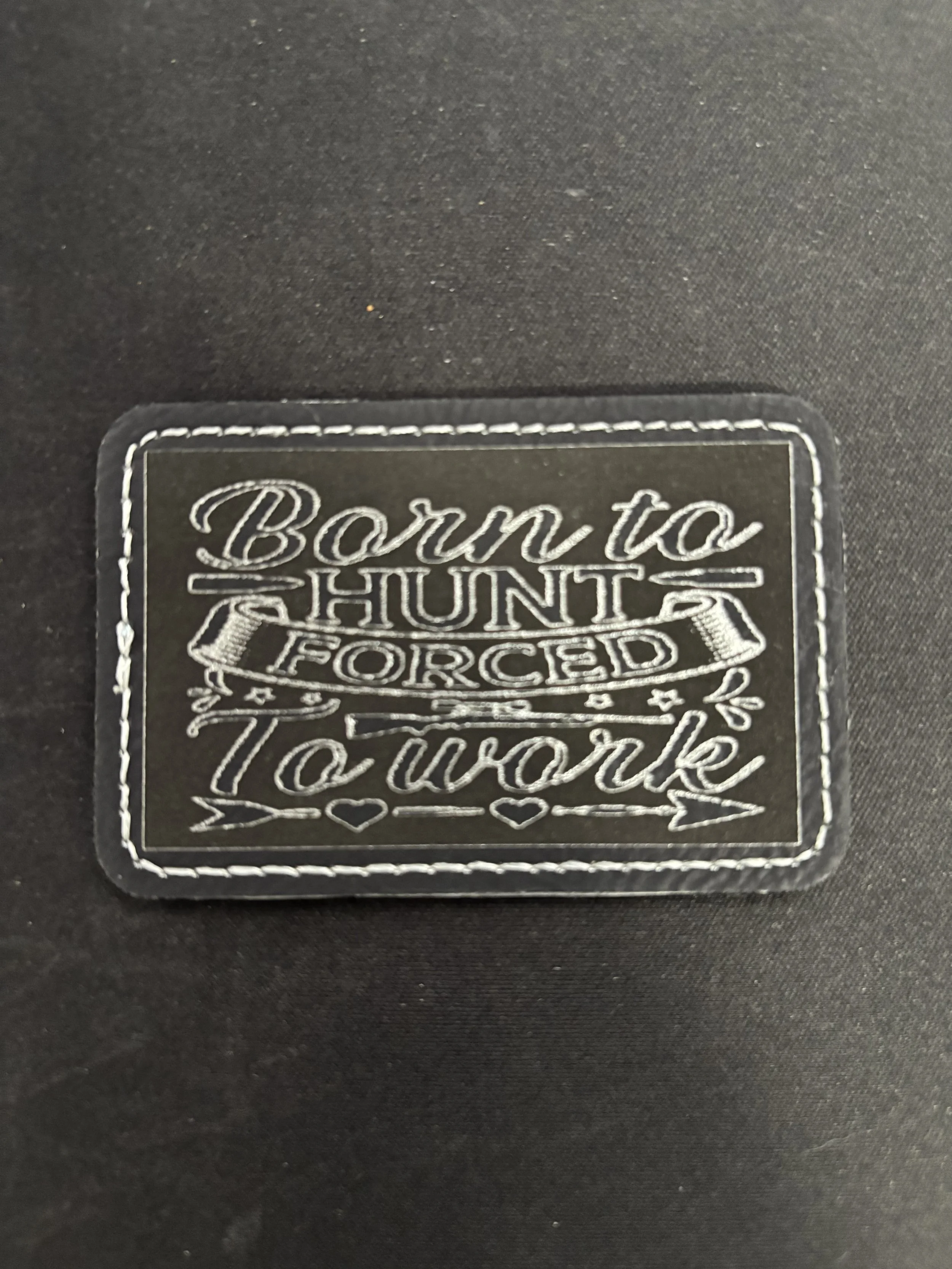 Clothing label with embroidered text that reads, 'Born to Hunt, For Real, T'.