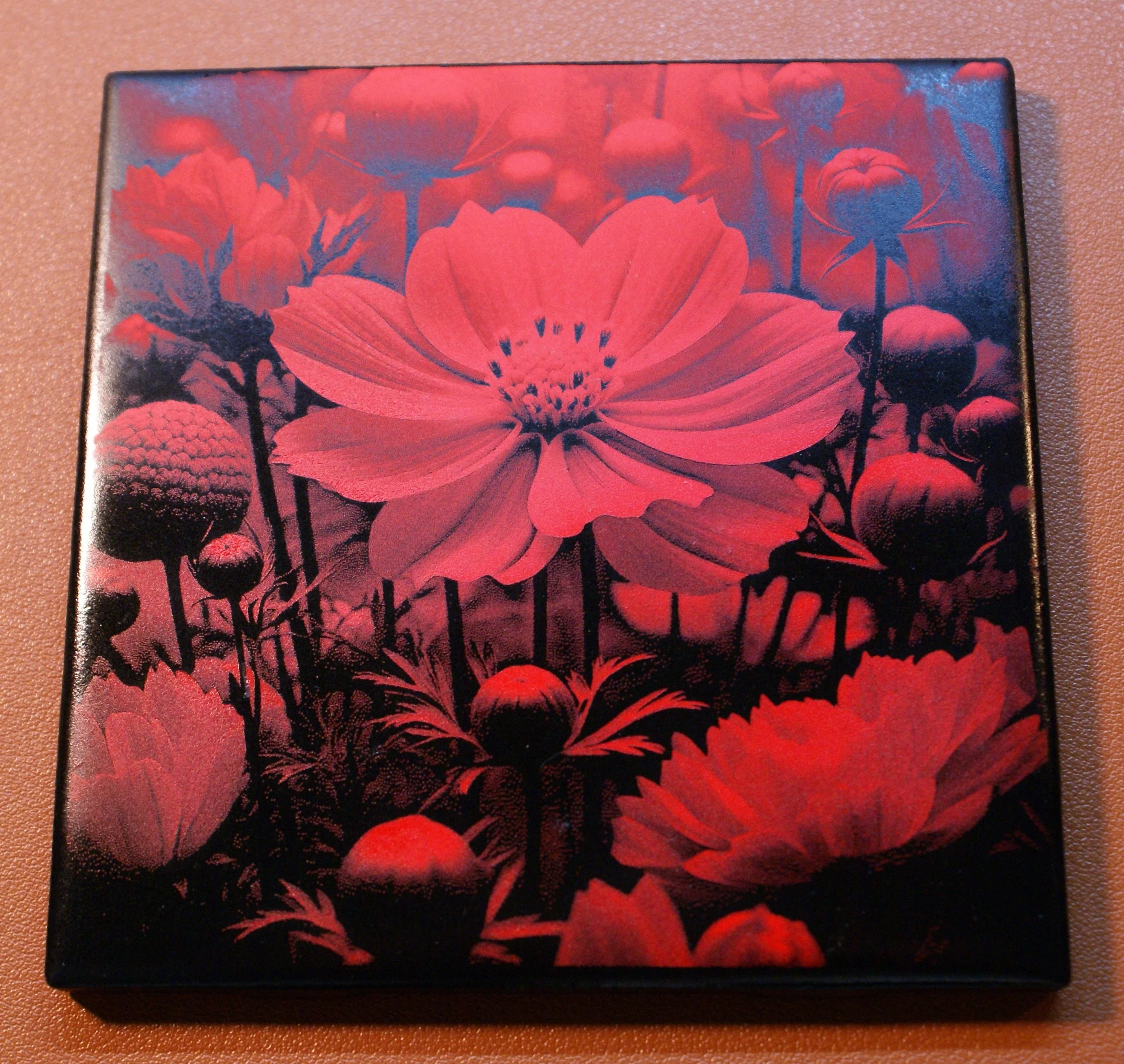 A box with a floral design featuring a large pink flower surrounded by smaller buds and flowers, depicted in a red and black color scheme.