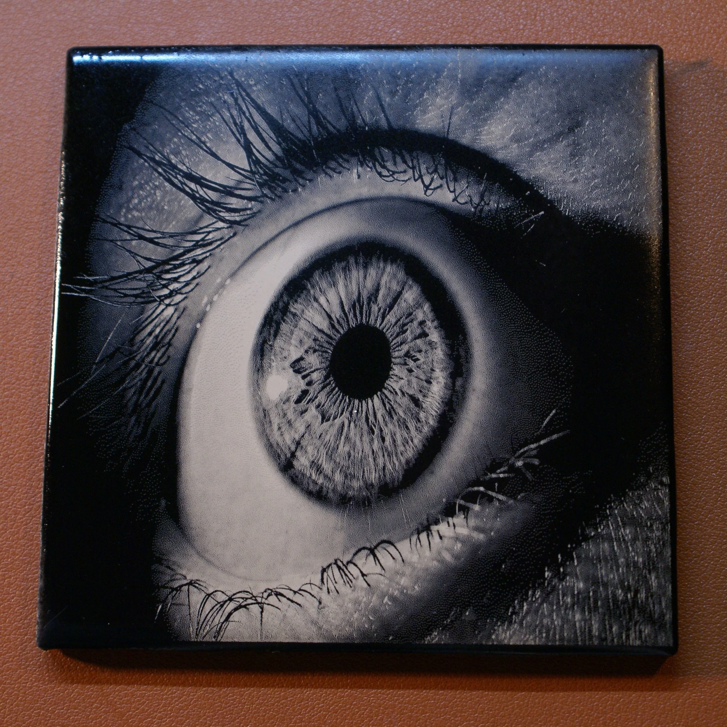 Close-up of a black and white artwork resembling a human eye with detailed eyelashes and iris.