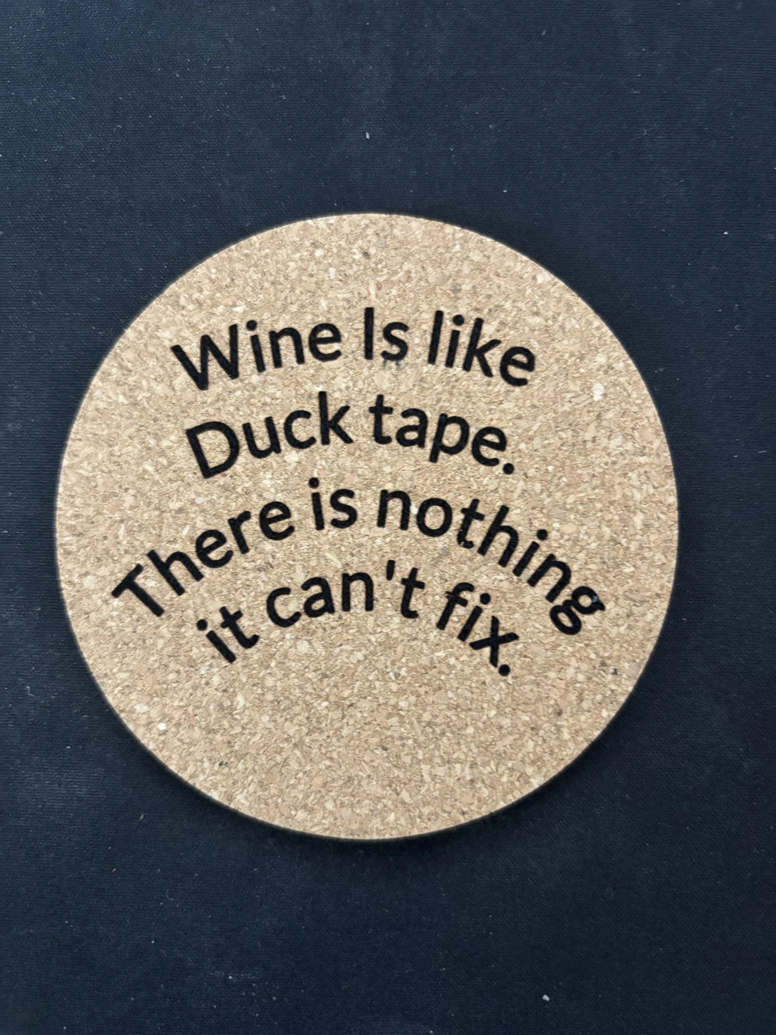 Round cork coaster with the humorous quote: 'Wine is like duck tape. There is nothing it can't fix.' printed on it.