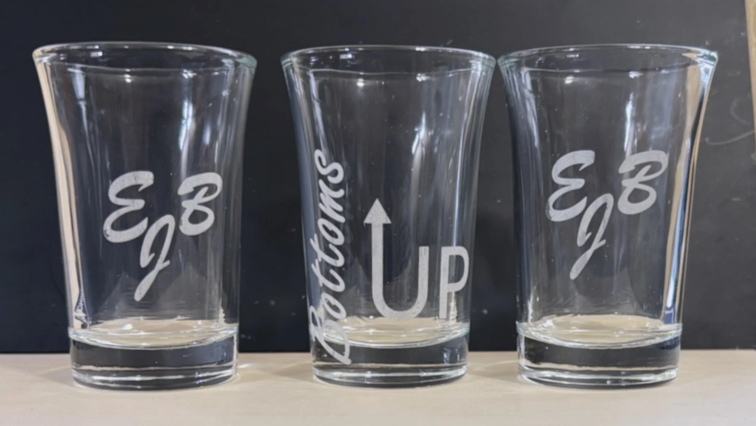 Three empty branded Starbucks plastic cups with CozEyE logo and arrow indicating to lift up, placed on a light-colored surface against a dark background.