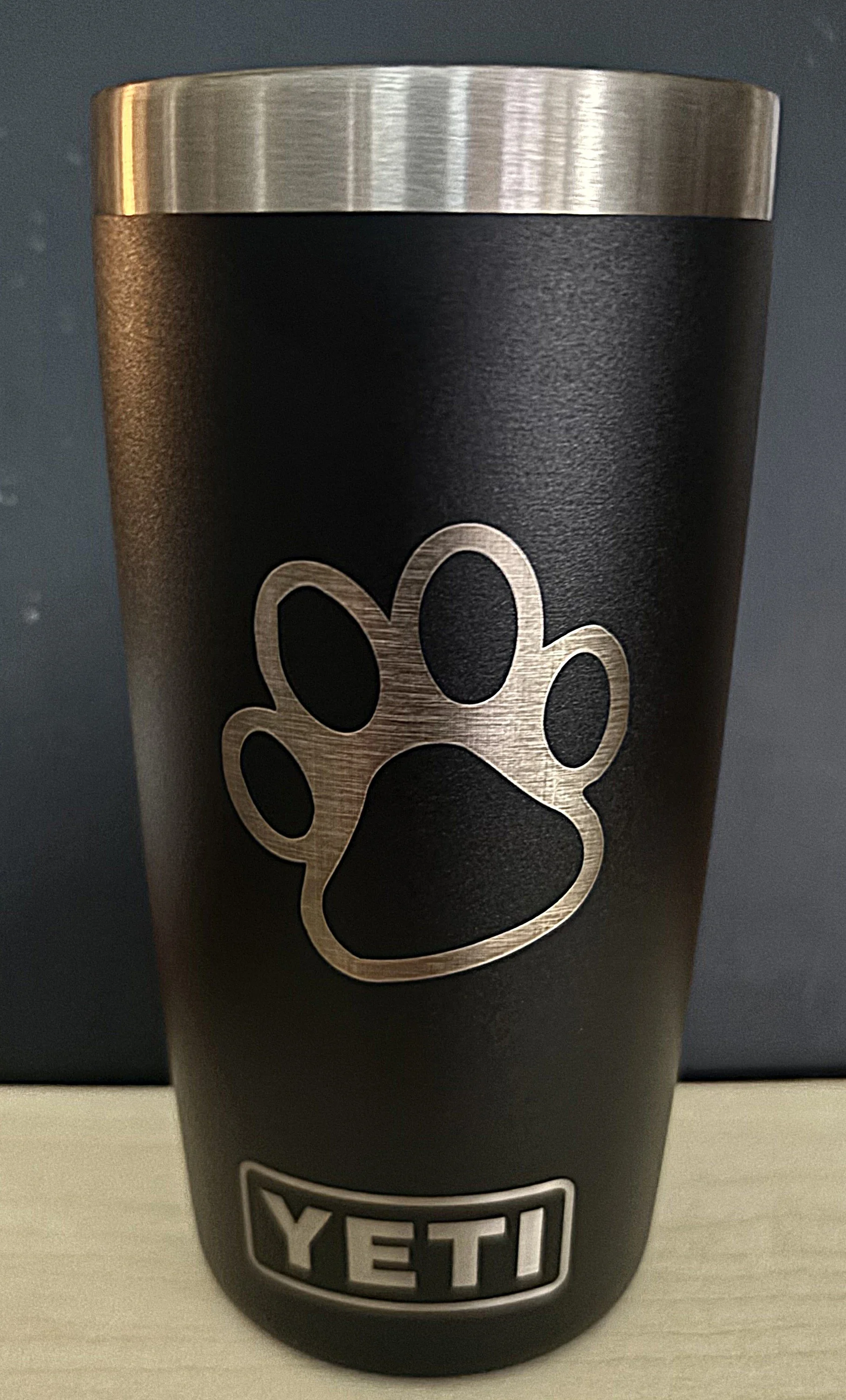 A black YETI tumbler with a silver paw print logo and the brand name YETI at the bottom.