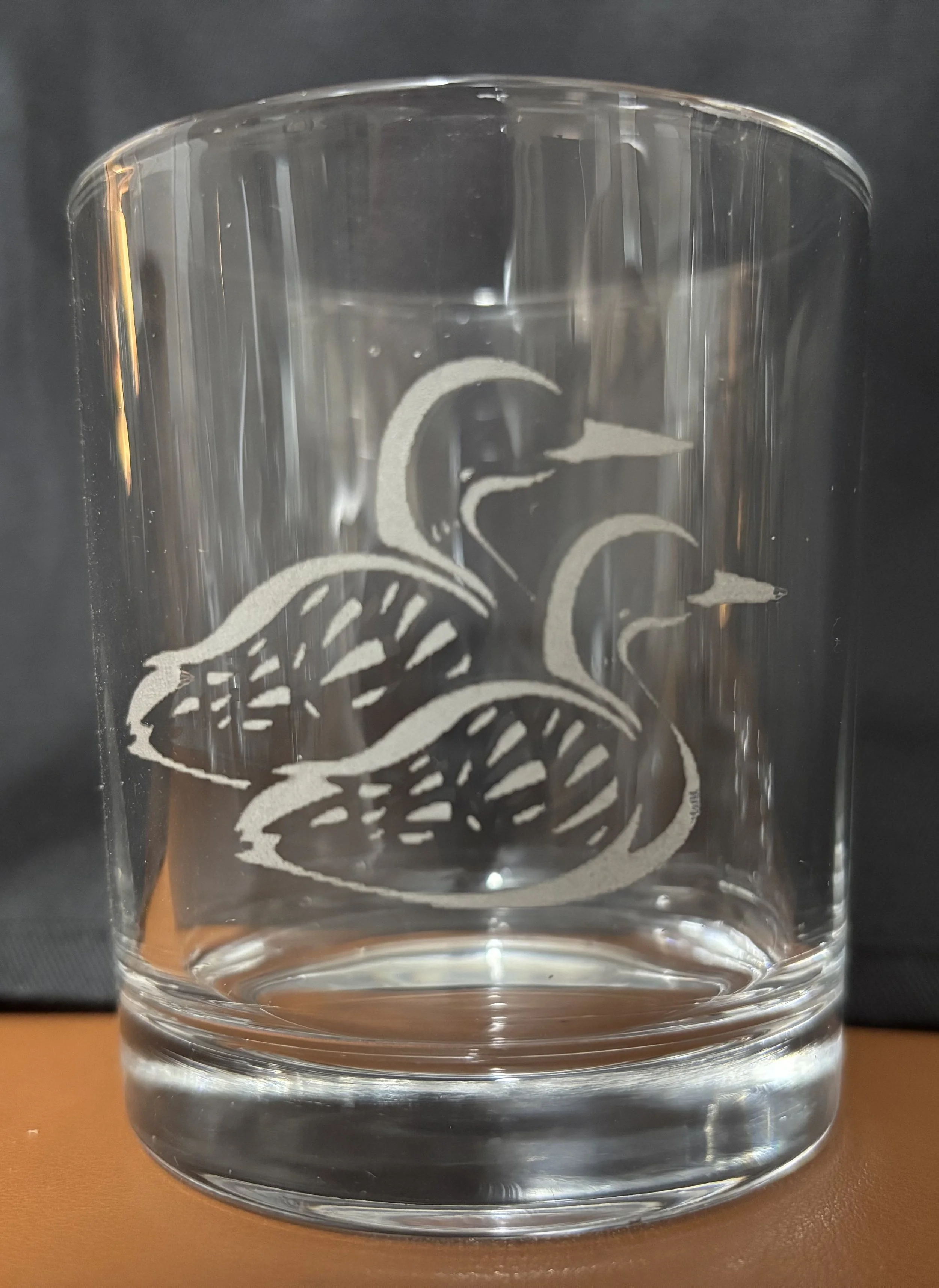 A clear glass tumbler with etched design of a snake.