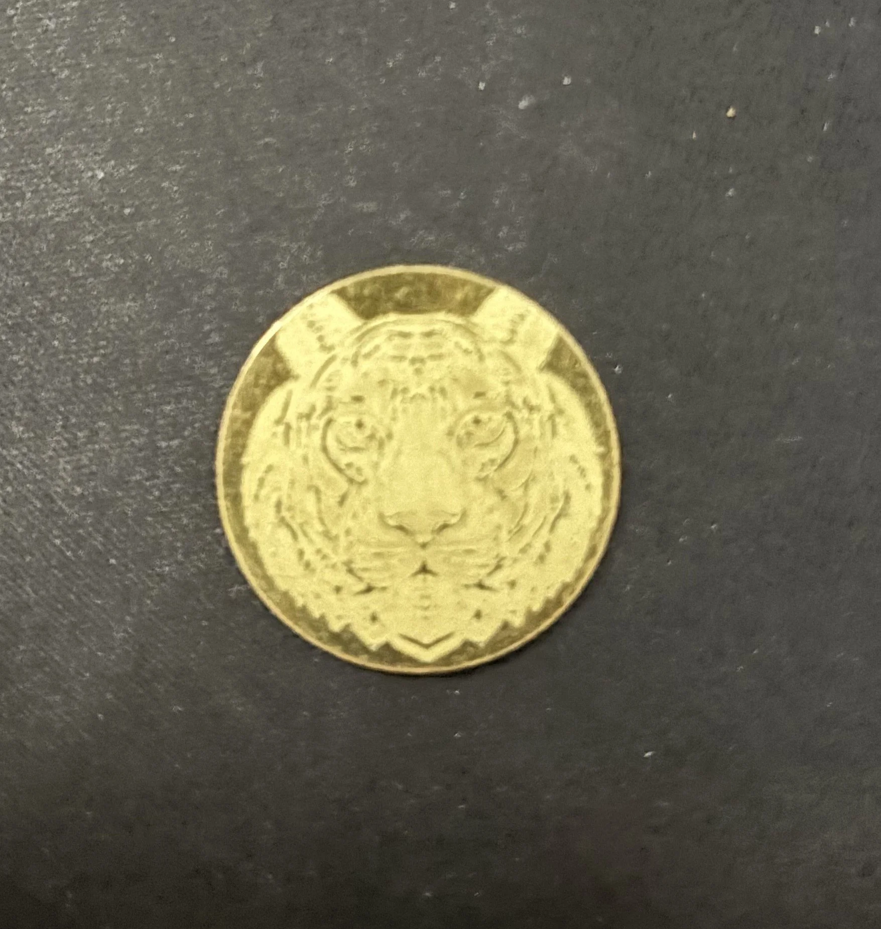 A gold-colored coin featuring the face of a tiger.