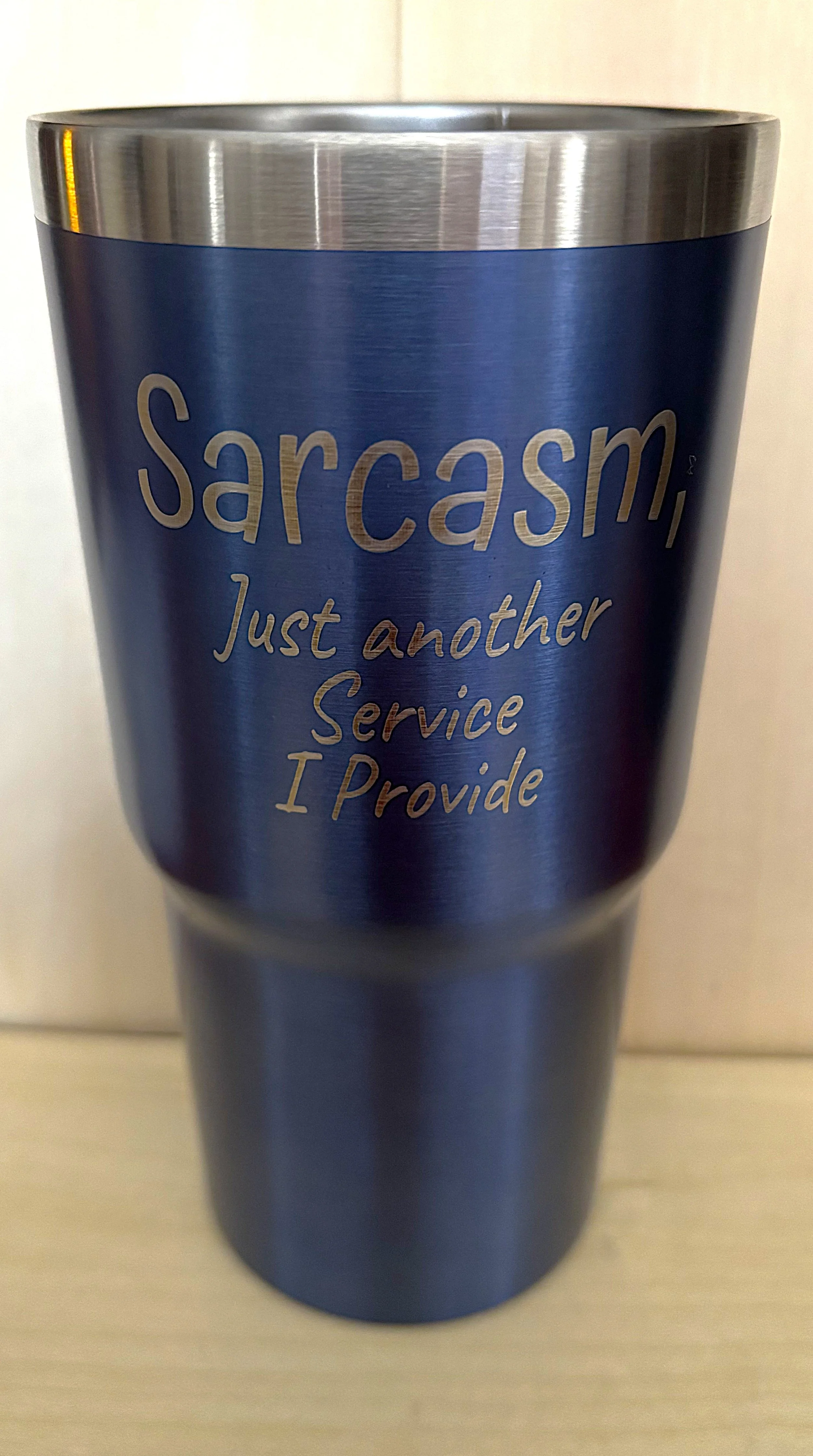 Blue stainless steel tumbler with silver lettering that says: "Sarcasm, Just another Service I Provide."