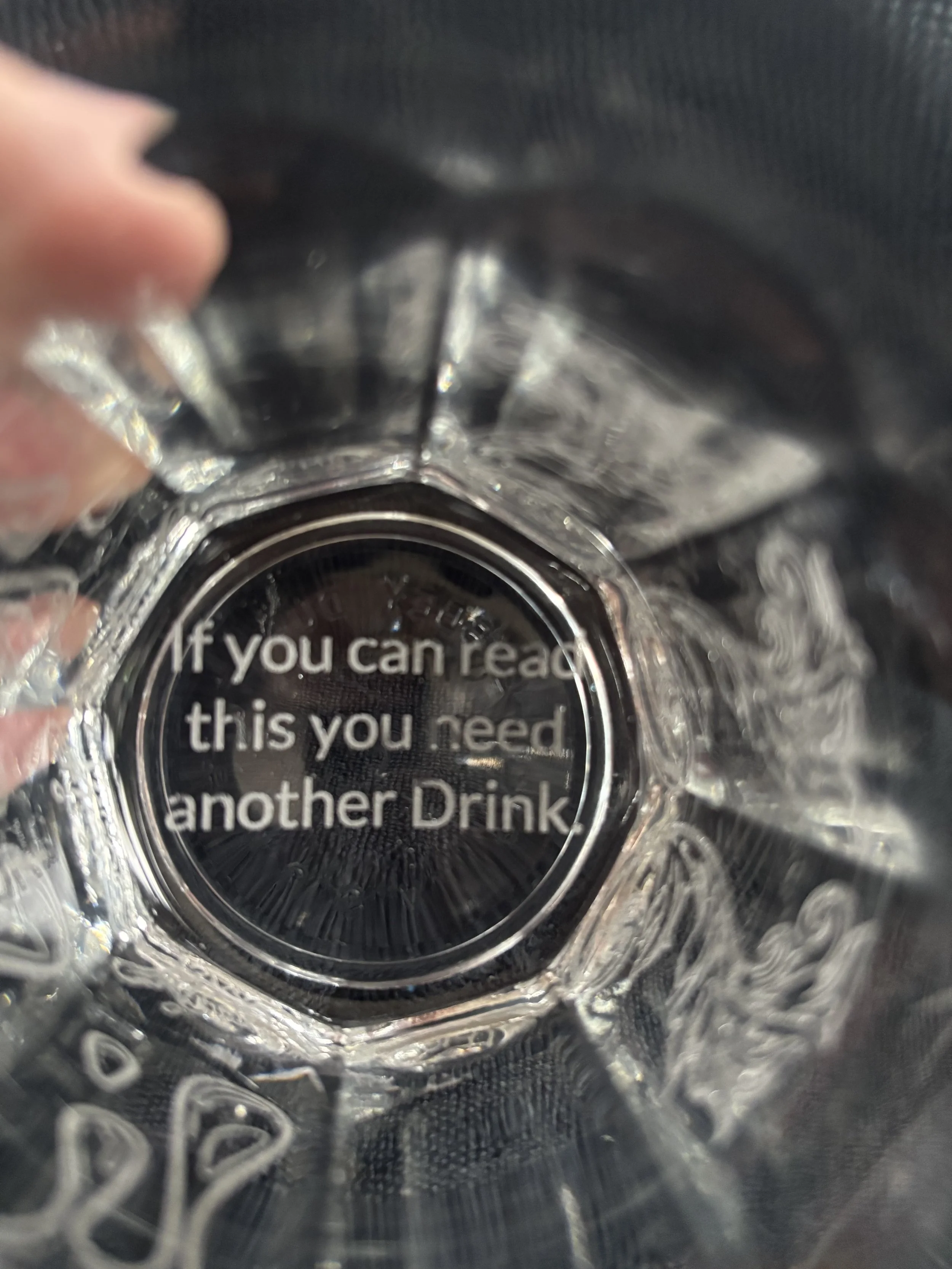 Inside a clear plastic water bottle, view of the bottom with a message that reads, "If you can read this you need another Drink."