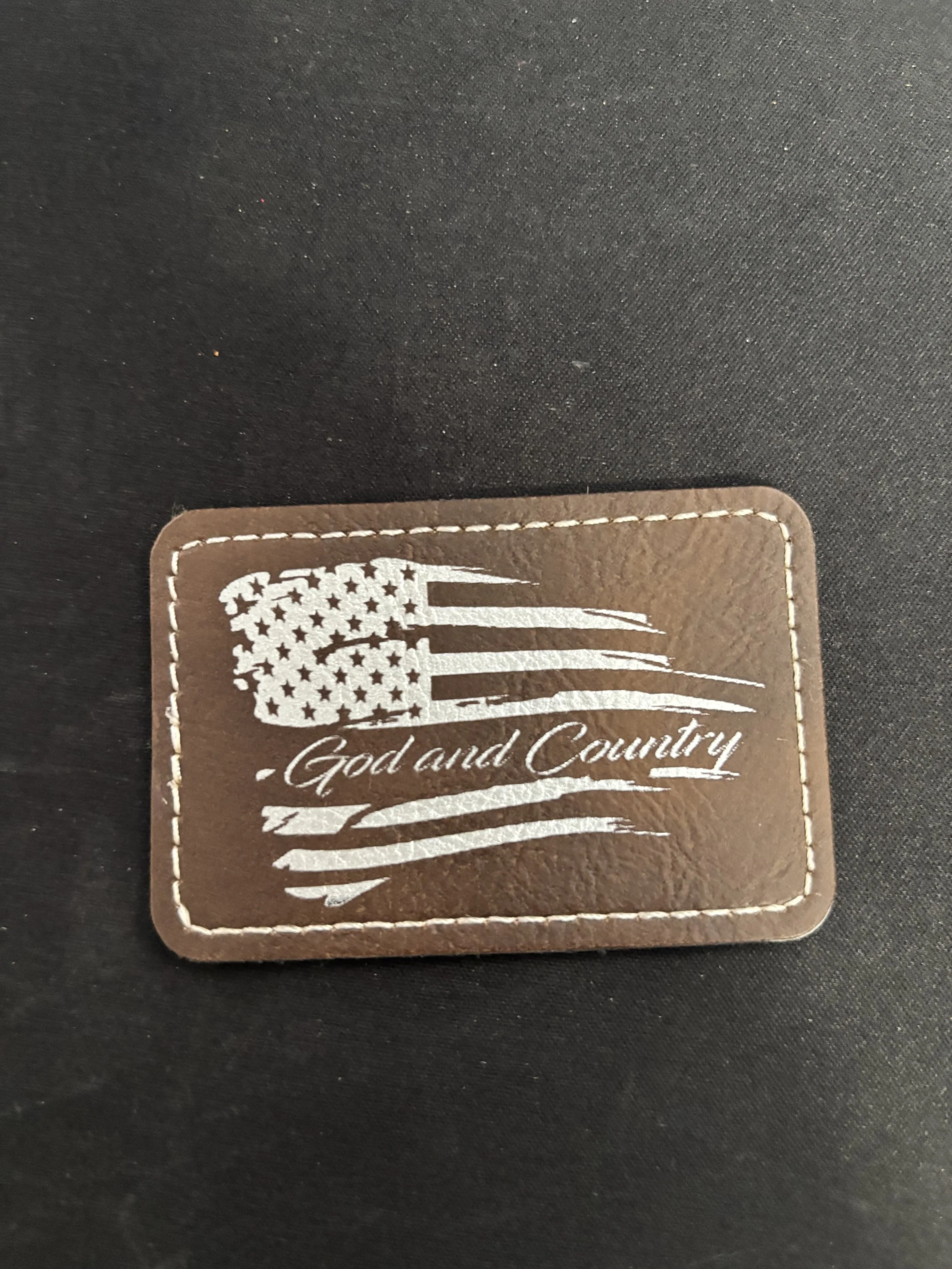 Leather patch with American flag and the words 'God and Country' on a black background.