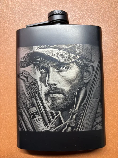 Engraved black flask featuring a bearded outdoorsman and hunting gear.