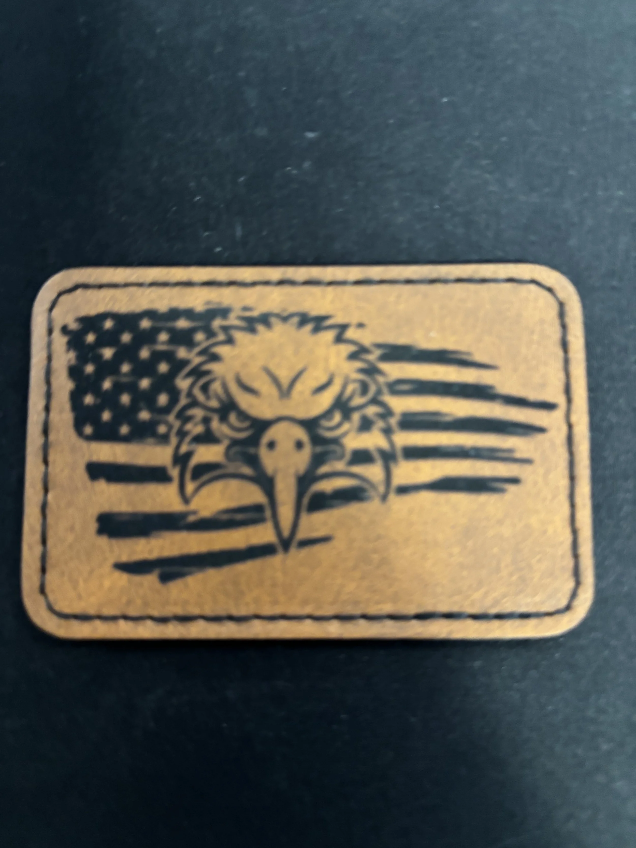 A leather patch featuring a bald eagle's head in front of a stylized American flag.
