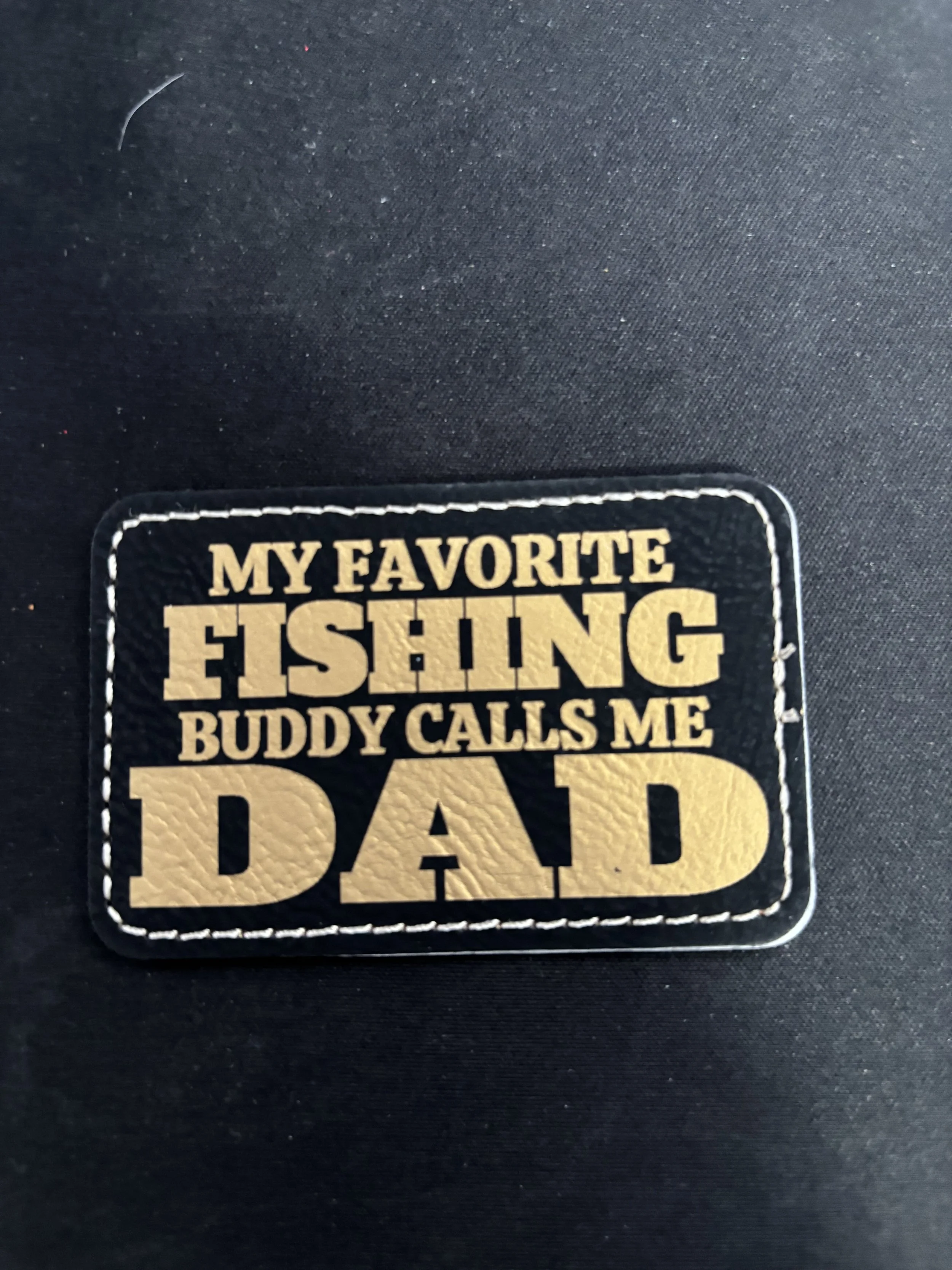 A patch with the text 'My favorite fishing buddy calls me dad' on a black background.