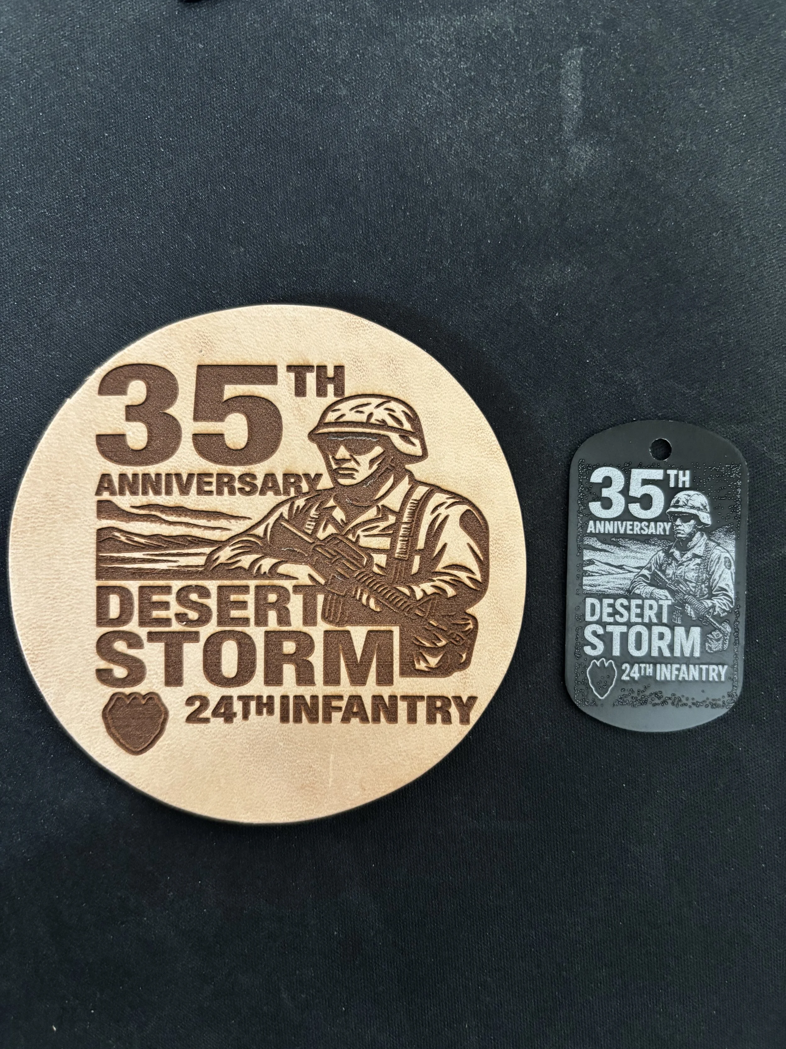 A circular wooden badge and a smaller black tag commemorate the 35th anniversary of Desert Storm and the 24th Infantry. The badge features an engraved image of a soldier in uniform holding a rifle, with text indicating '35th Anniversary' and 'Desert 