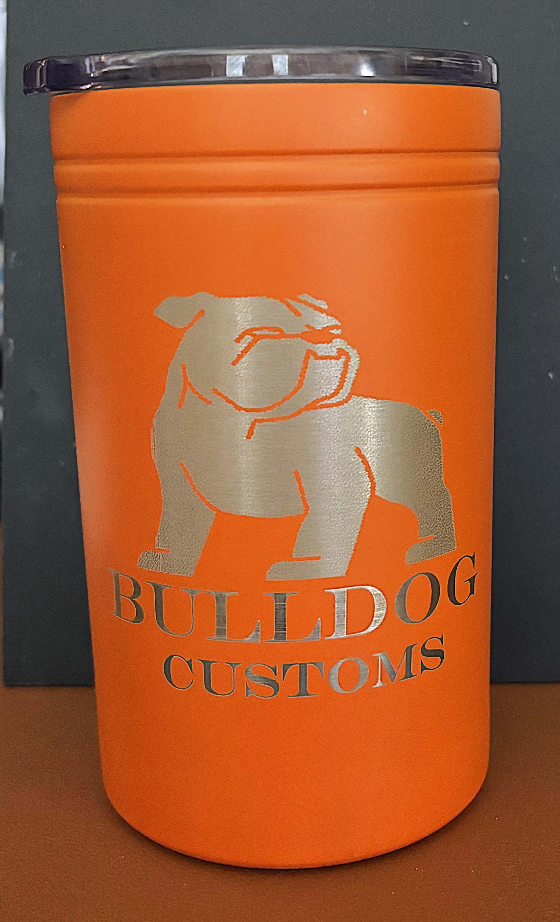An orange travel mug with a silver outline of a bulldog and the words "BULLDOG CUSTOMS" printed on it.