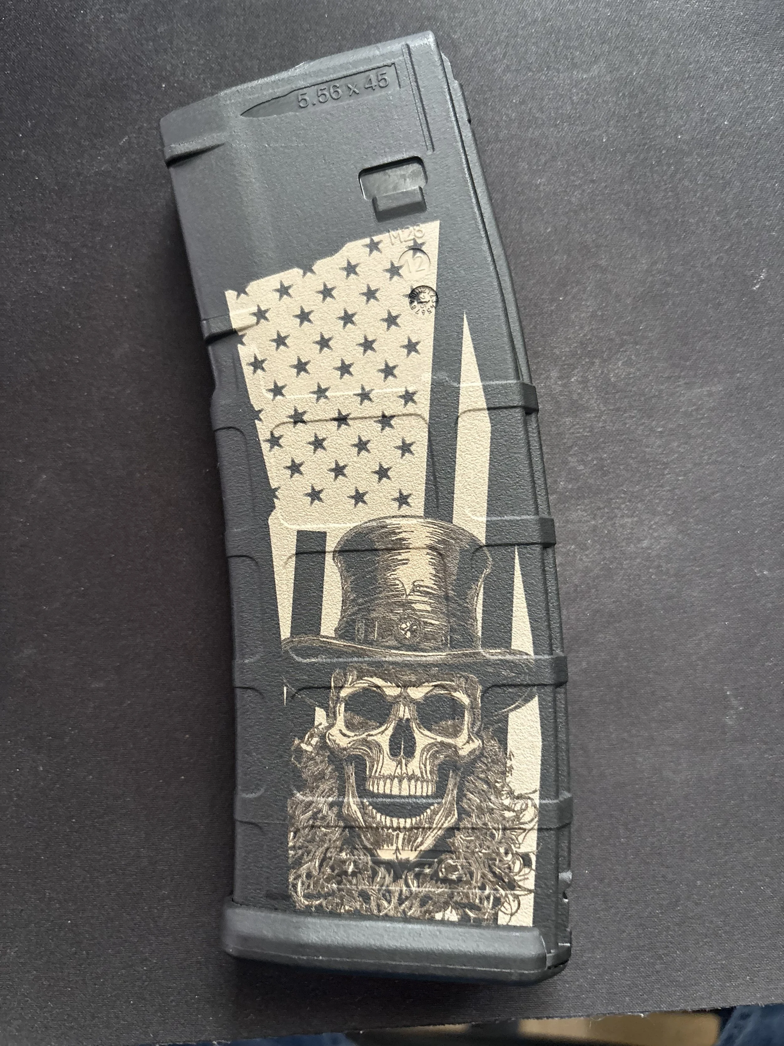 A magazine with a design of an American flag, a skull with a top hat, and curly hair, printed in beige and black on a dark background.