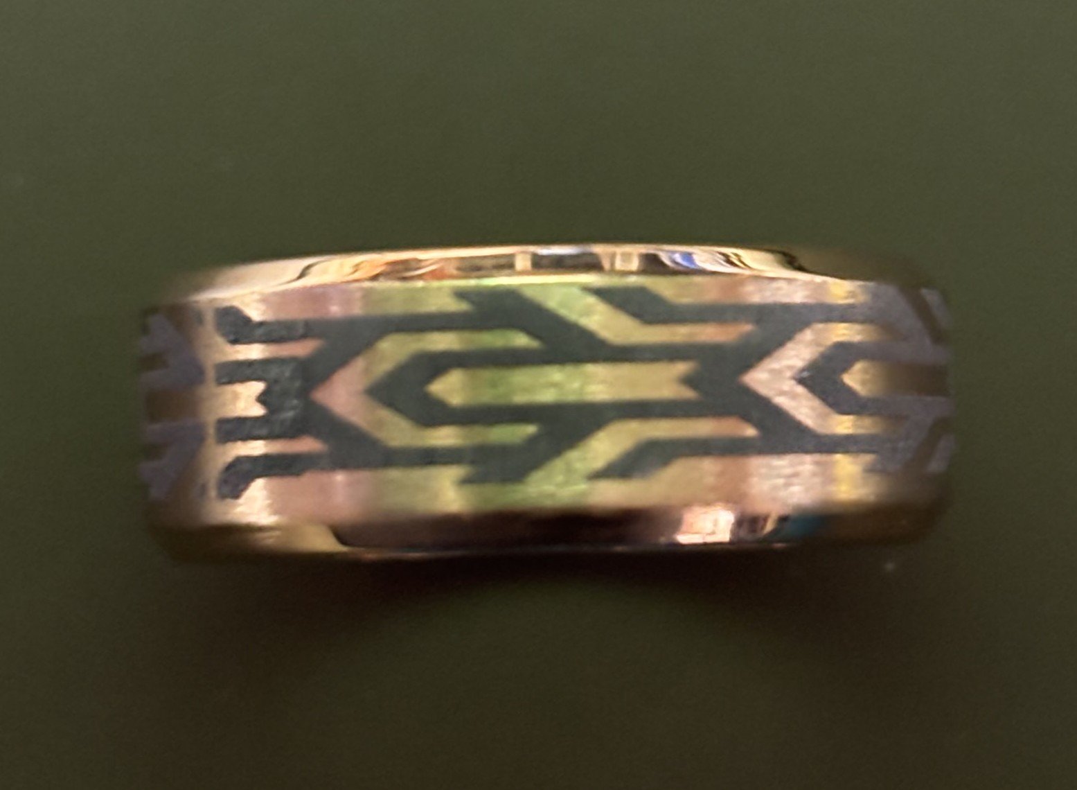 Close-up of a metal ring with a geometric pattern engraved on its surface.