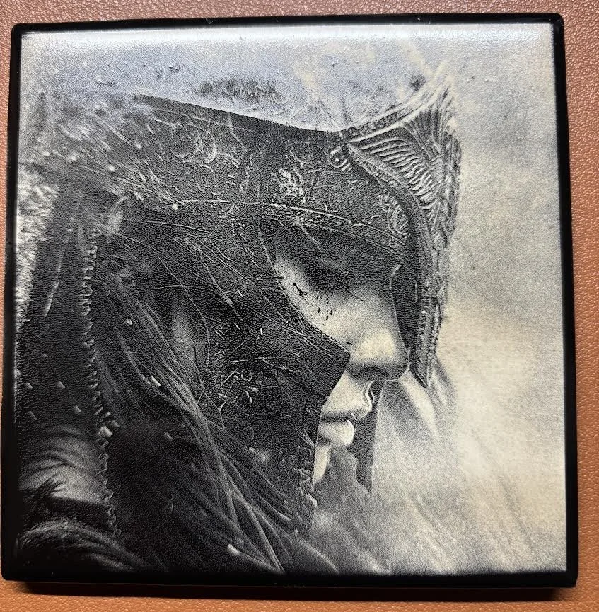 Close-up of a person wearing a futuristic helmet with intricate details, with a somber expression and eyes closed.