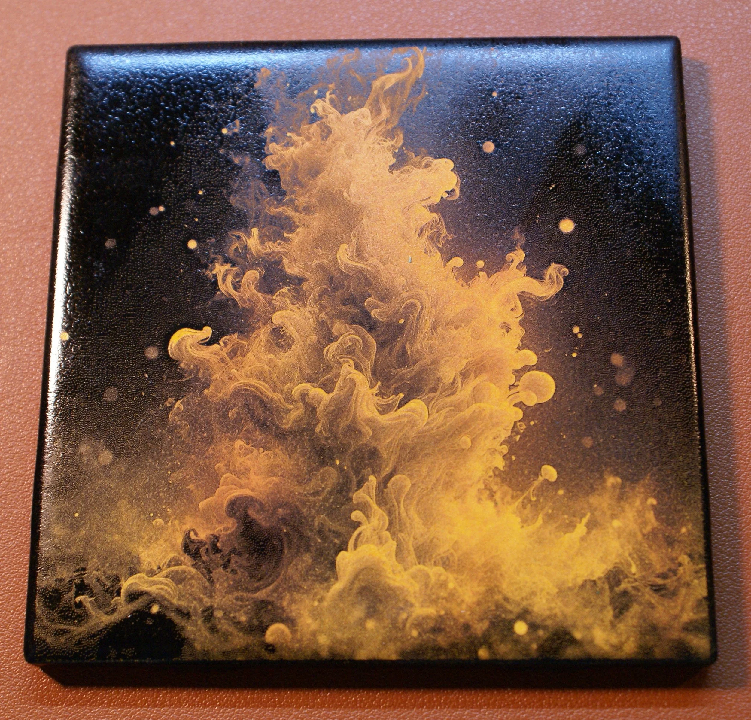 Black box with a swirling, yellowish-orange smoke or ink design on the cover.