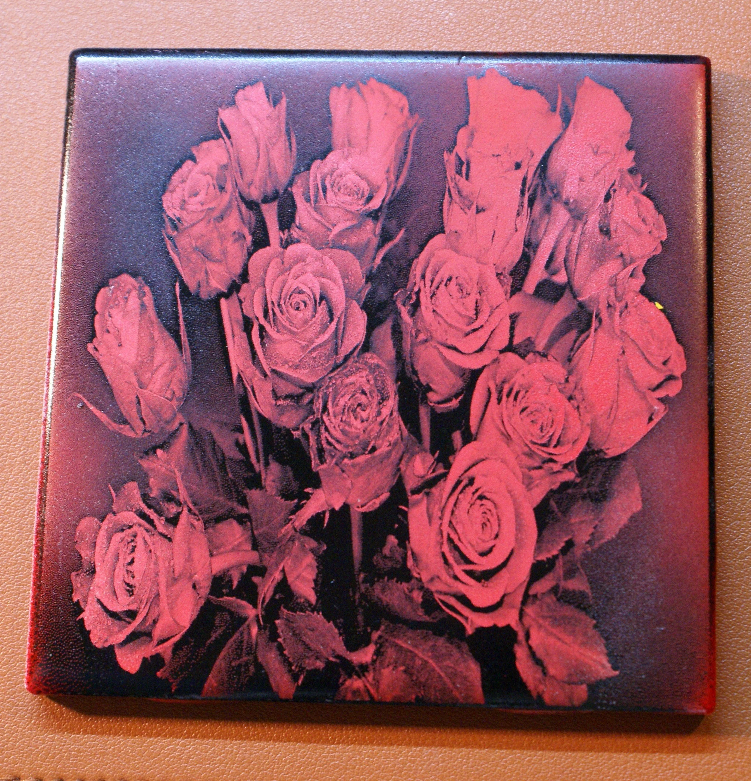 A square black canvas featuring a red monochrome image of multiple roses in full bloom, arranged in a bouquet.