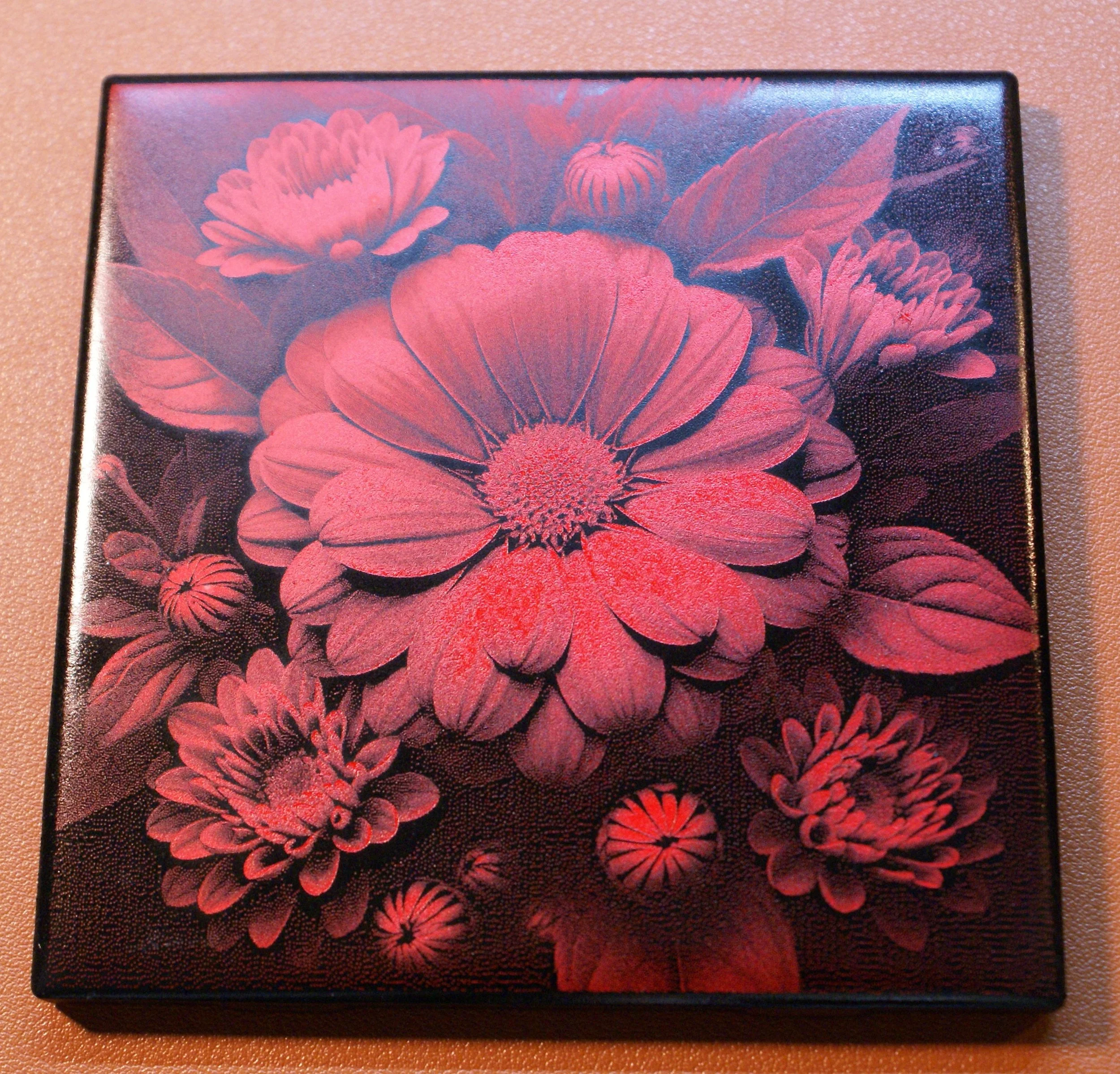 A decorative box featuring an illustration of various pink and red flowers with leaves against a dark background.