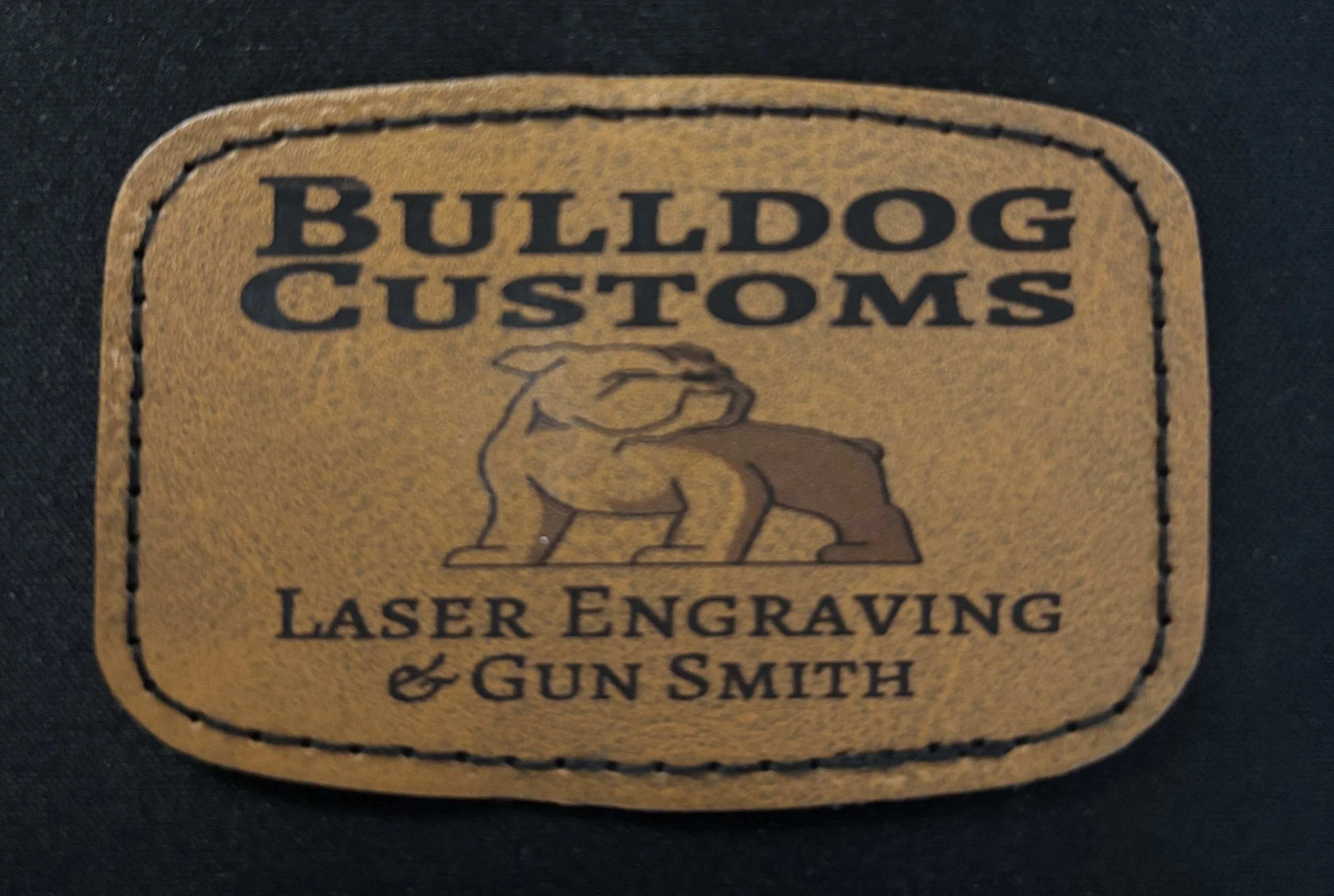 Leather patch with the text 'BULLDOG CUSTOMS' at the top, a bulldog graphic in the middle, and 'LASER ENGRAVING & GUN SMITH' at the bottom.