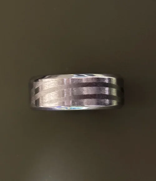 This brushed metal ring features a clean, industrial design with precision-cut parallel grooves encircling its surface. Crafted from durable, stainless steel it offers a sleek, modern profile with subtle texture and high-end finish. 