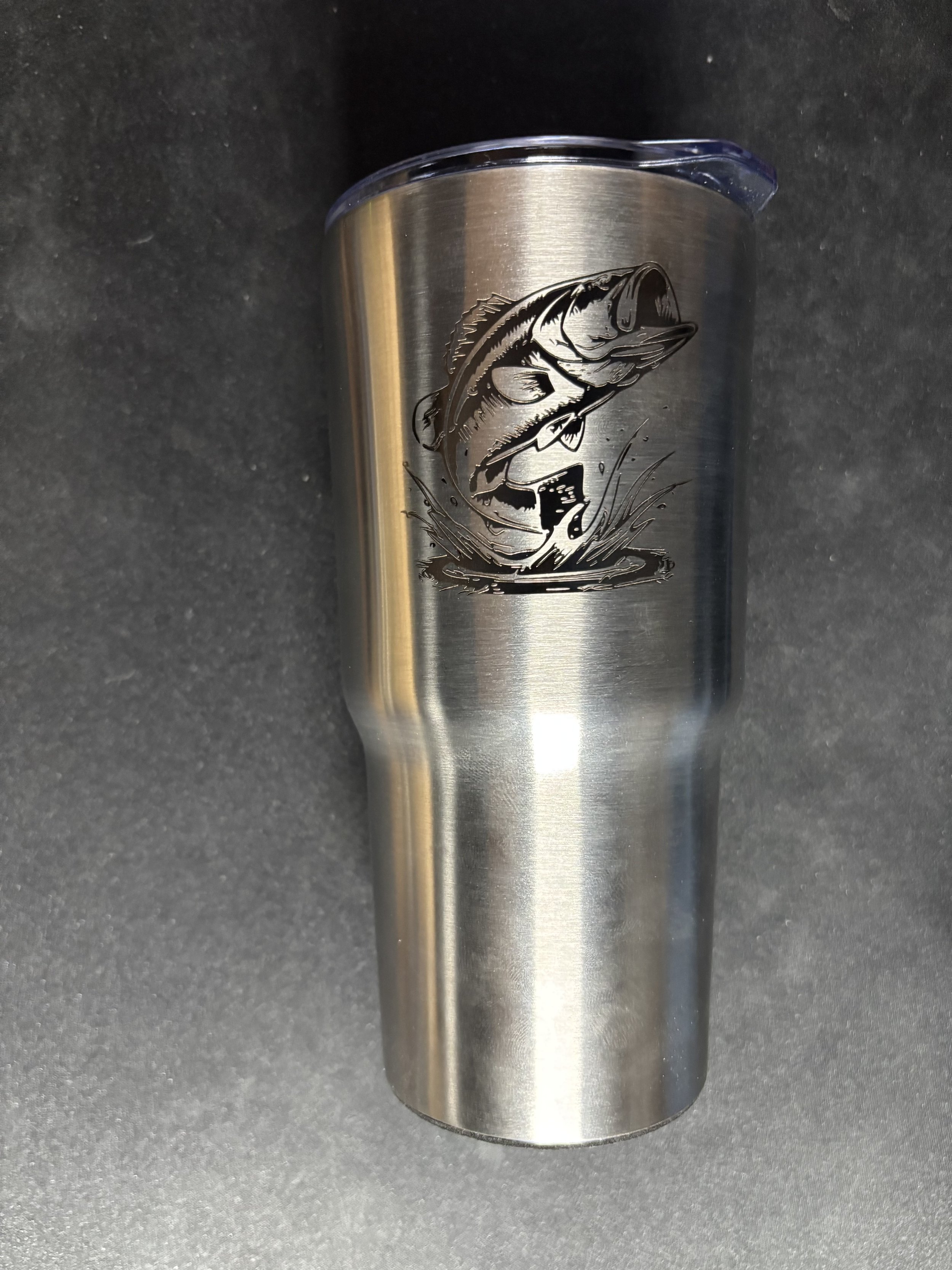 A stainless steel tumbler with a black illustration of a bass fish jumping out of water.