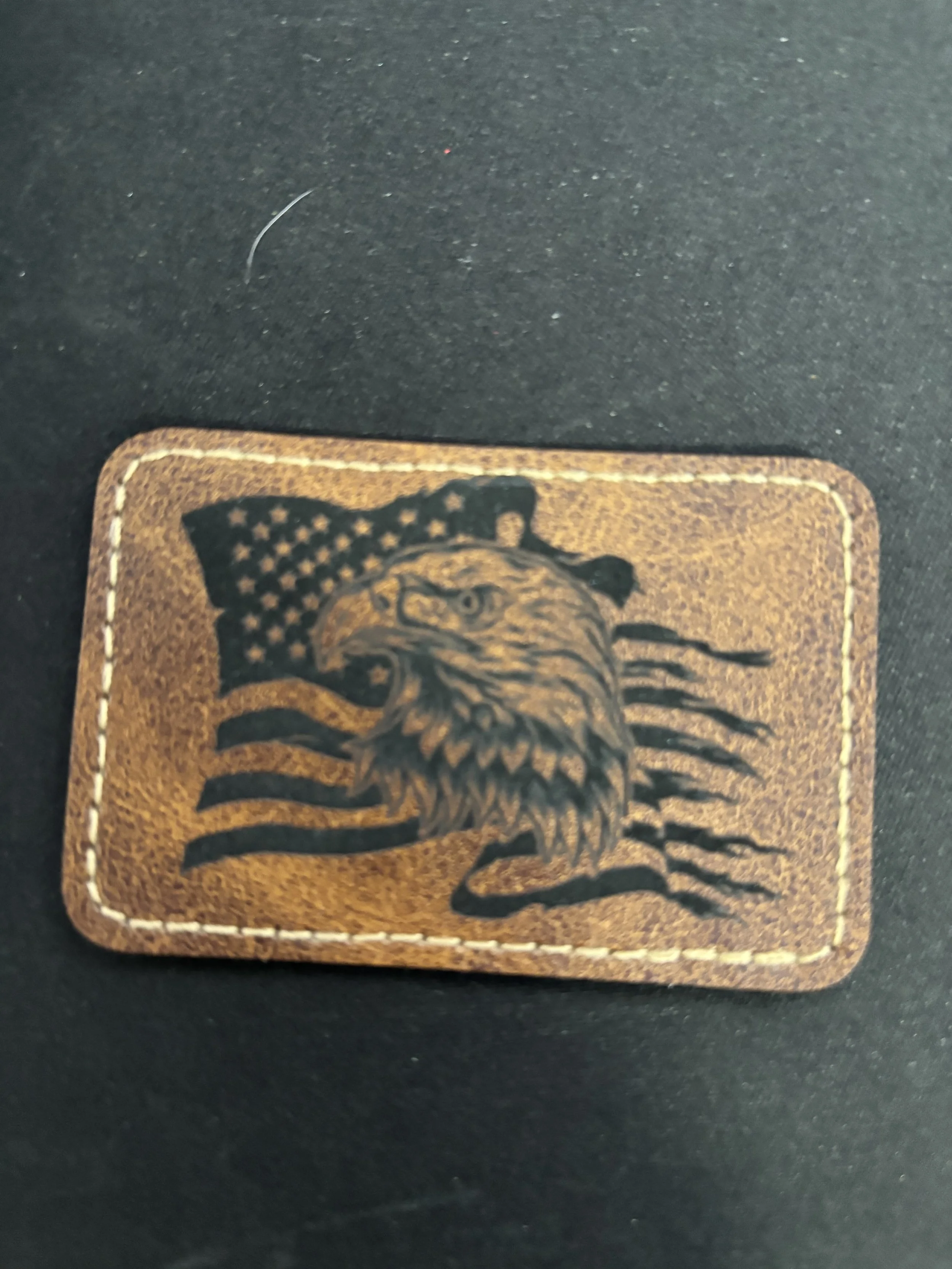 A leather patch with an eagle's head and an American flag in the background.