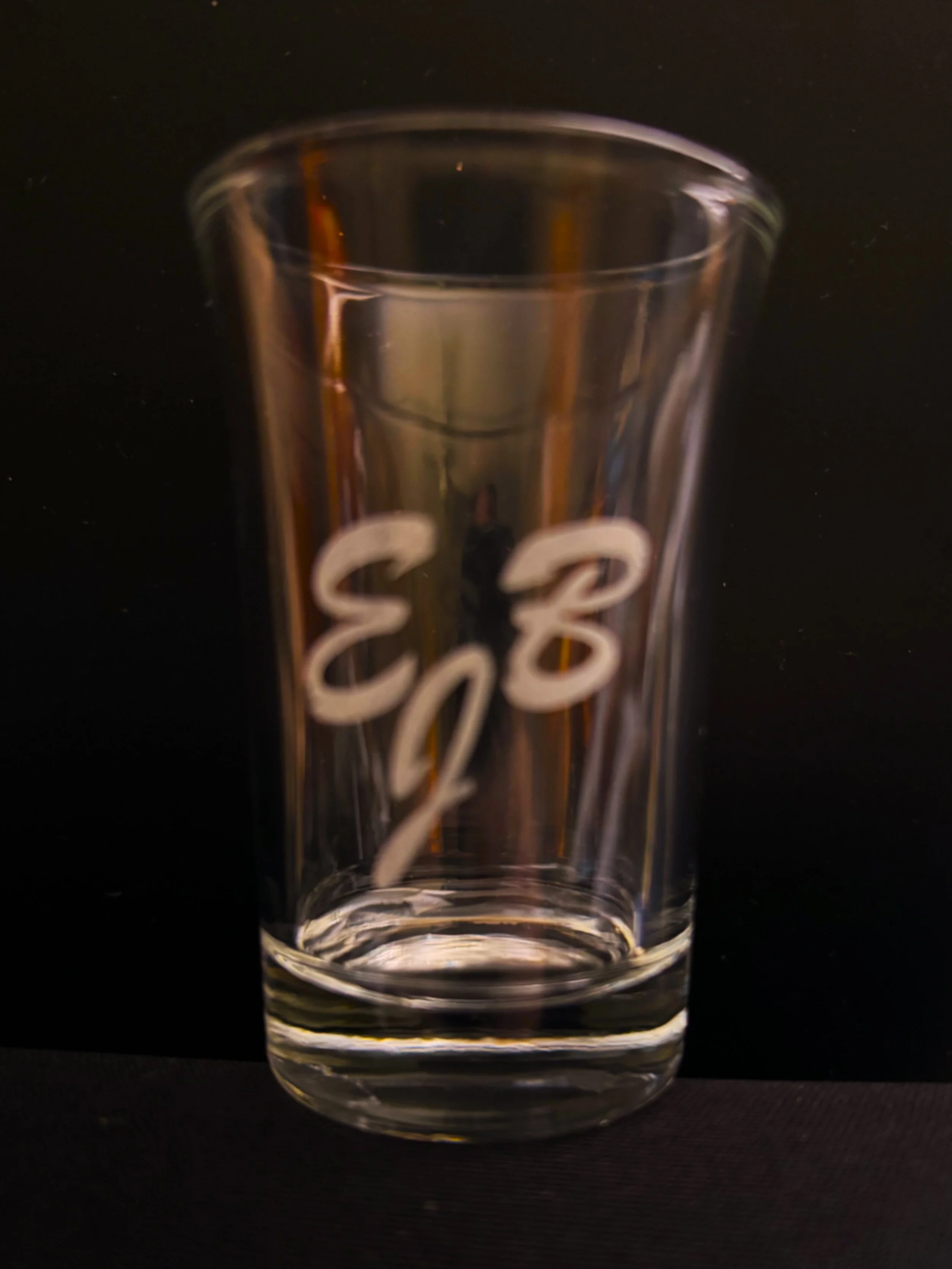 A clear glass with a slightly flared top and 'E=2' written on it in white, set against a black background.