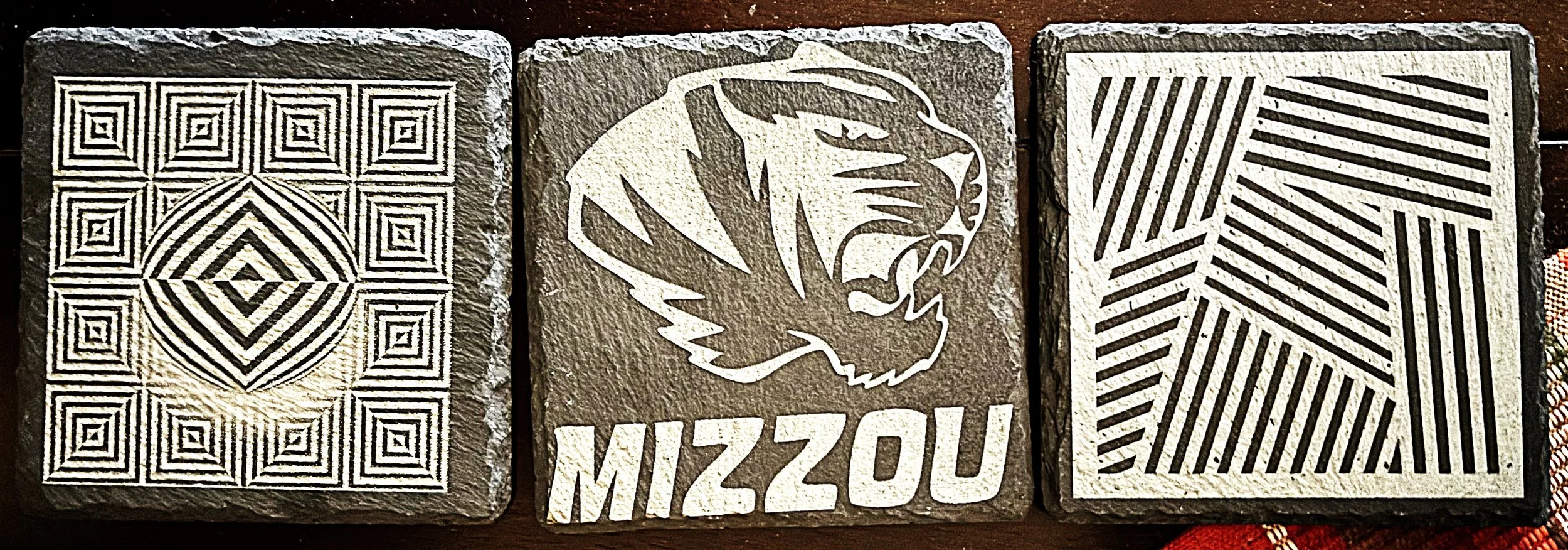 Three decorative tiles with black and white geometric and animal designs, labeled "MIZZOU" in the center tile.