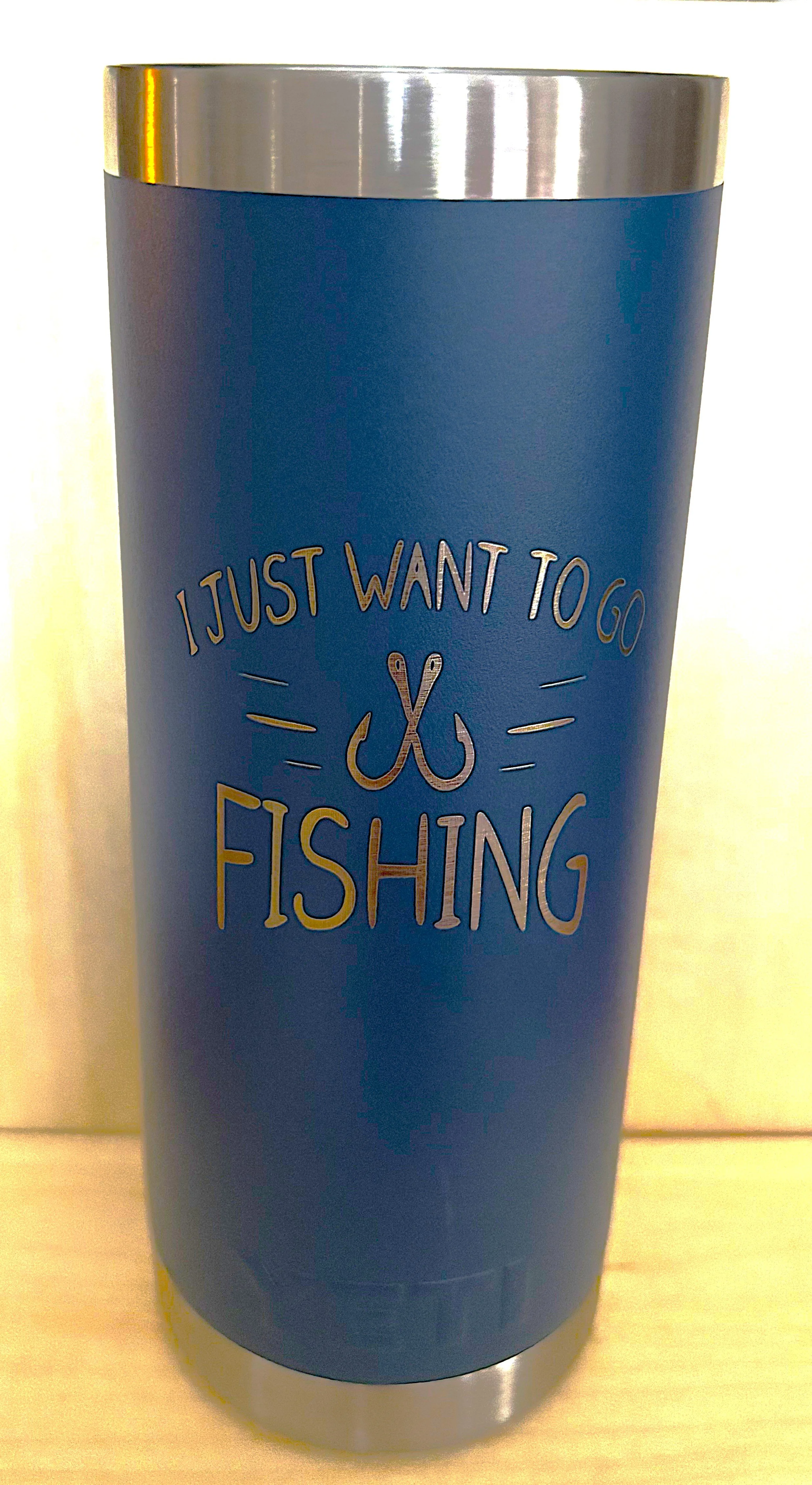Blue travel tumbler with a silver top and bottom, featuring text that reads 'I just want to go fishing' with a fish hook illustration.