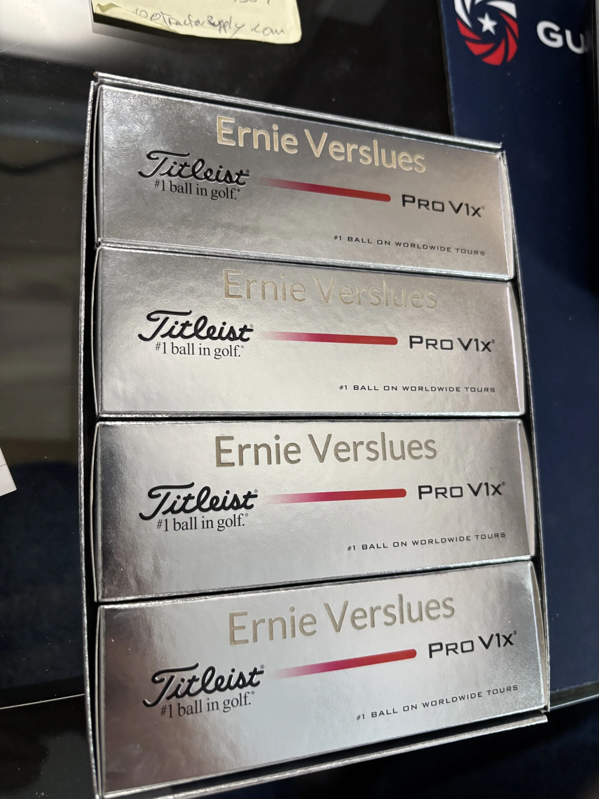 Four boxes of Titleist Ernie Els Pro V1x golf balls stacked on a dark surface. The boxes are silver with black and red text.