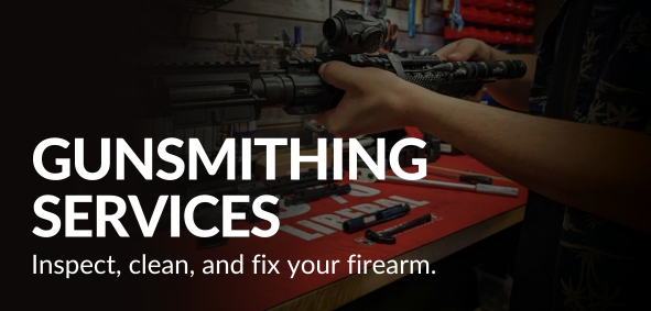 A person inspecting a rifle at a gunsmithing workbench with tools and firearm parts.