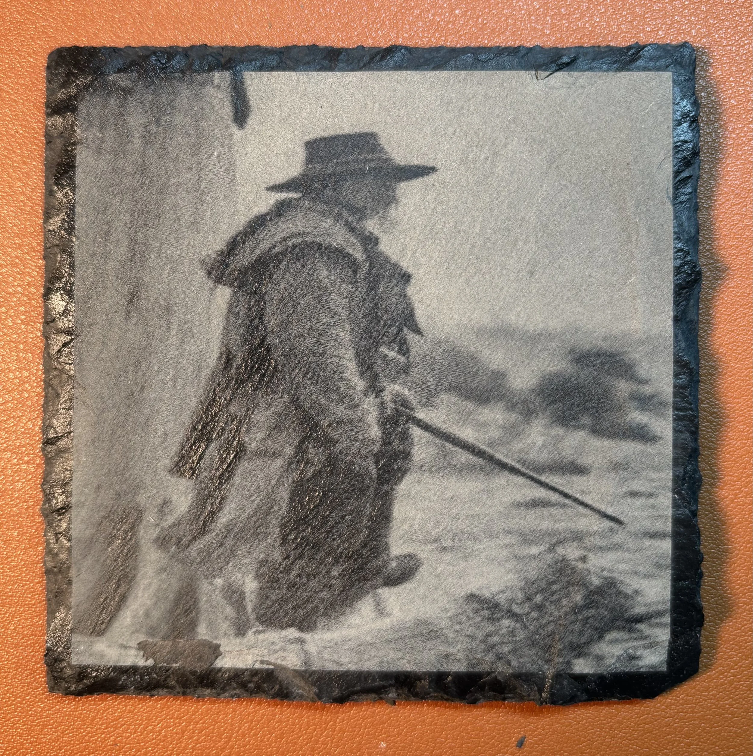 Black and white photo of a person in historical clothing holding a spear, standing in a snowy landscape, with a second person partially visible.